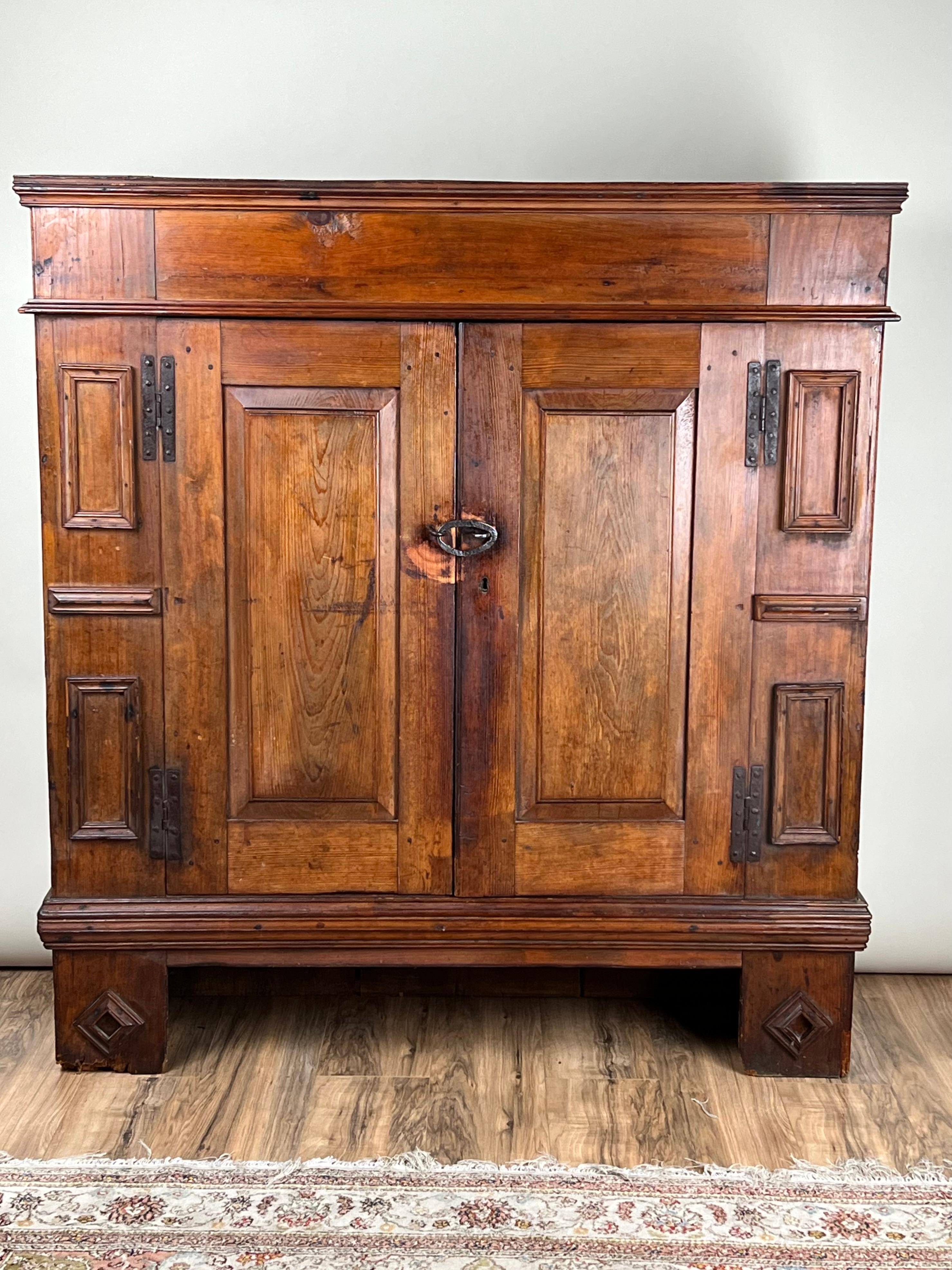 Questa antica credenza continentale in pino, probabilmente tedesca e risalente agli inizi del XVIII secolo, è un ottimo esempio di artigianato europeo. L'armadio presenta pesanti ante a pannelli incorniciate da dettagli modanati, con cerniere