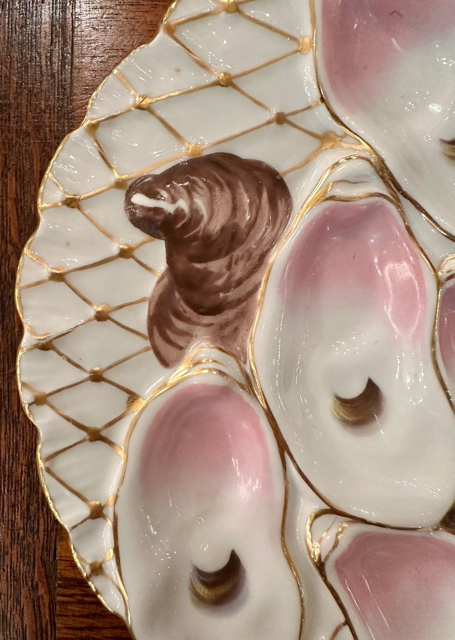 Antique Continental Porcelain Netted Turkey Pattern Oyster Plate, Circa 1890.
Hand-Painted Pink and Brown on a White Background with Fine Gold Net Details.