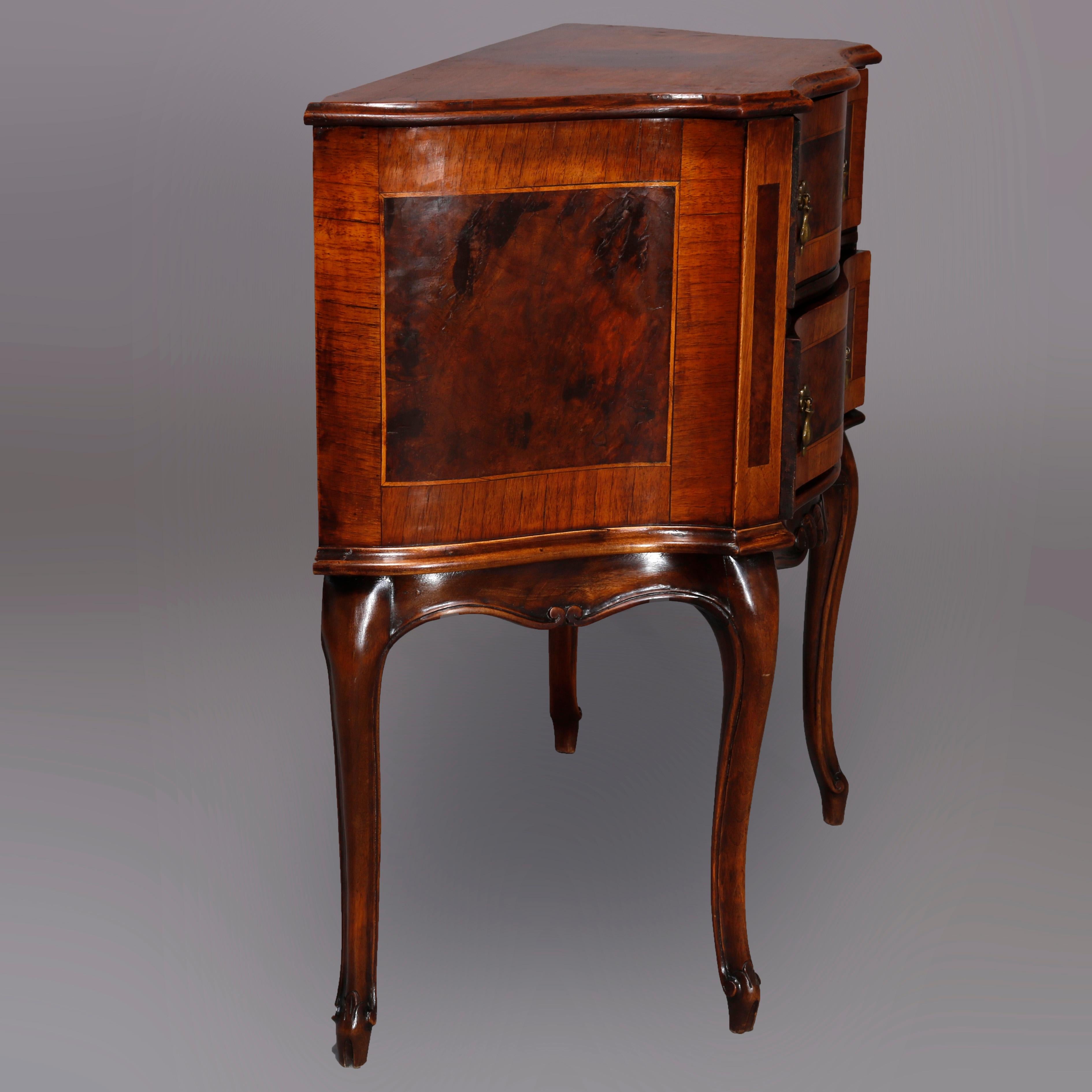An antique Continental side stand offers walnut construction in serpentine form having shaped top over burl inlaid and crossbanded double drawer chest having foliate carved apron, raised on cabriole legs terminating in scroll feet, circa