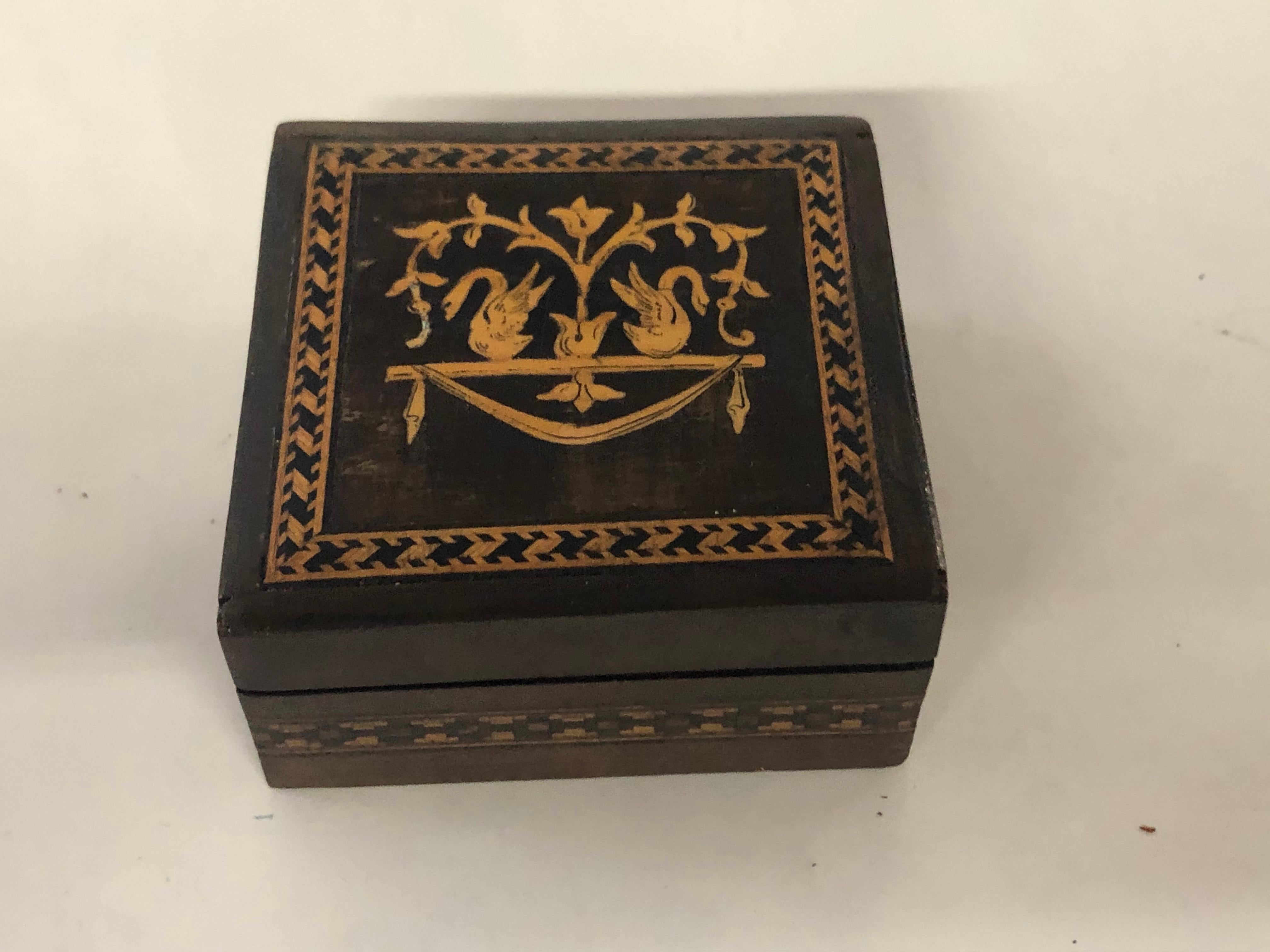 Antique square marquetry inlaid walnut trinket box or snuff box with fabulous satinwood swans flanking a bellflower decoration.
A/F - A small quarter inch portion of inlay on the left swan and a slight shrinkage, age-related crack on bottom noted