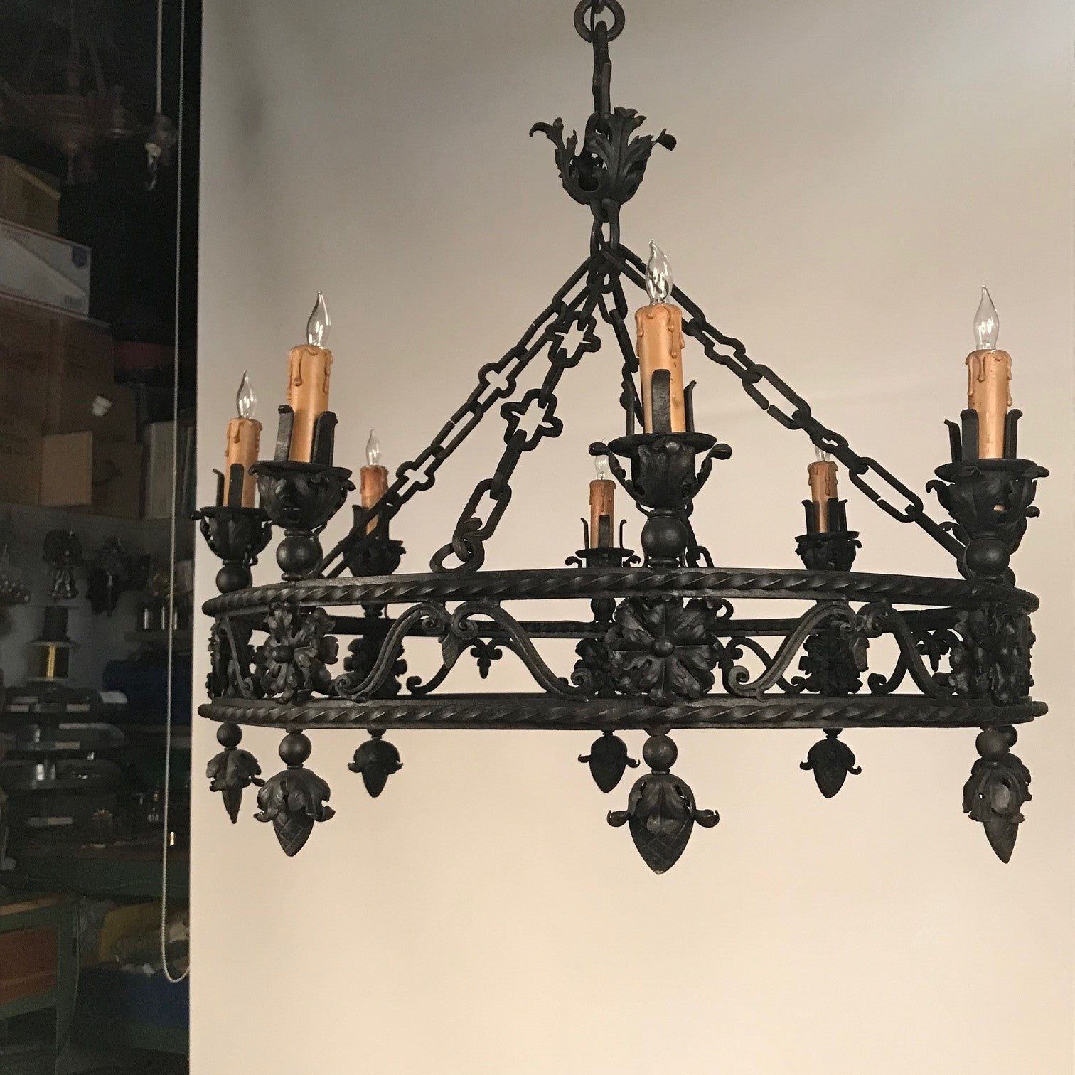 This circular wrought iron chandelier is formed structurally by two round twisted parallel bands connected by scrolling bars and support the eight candle sockets. The whole is ornamented with hand-formed leaves. The leaves, rosettes and pendent