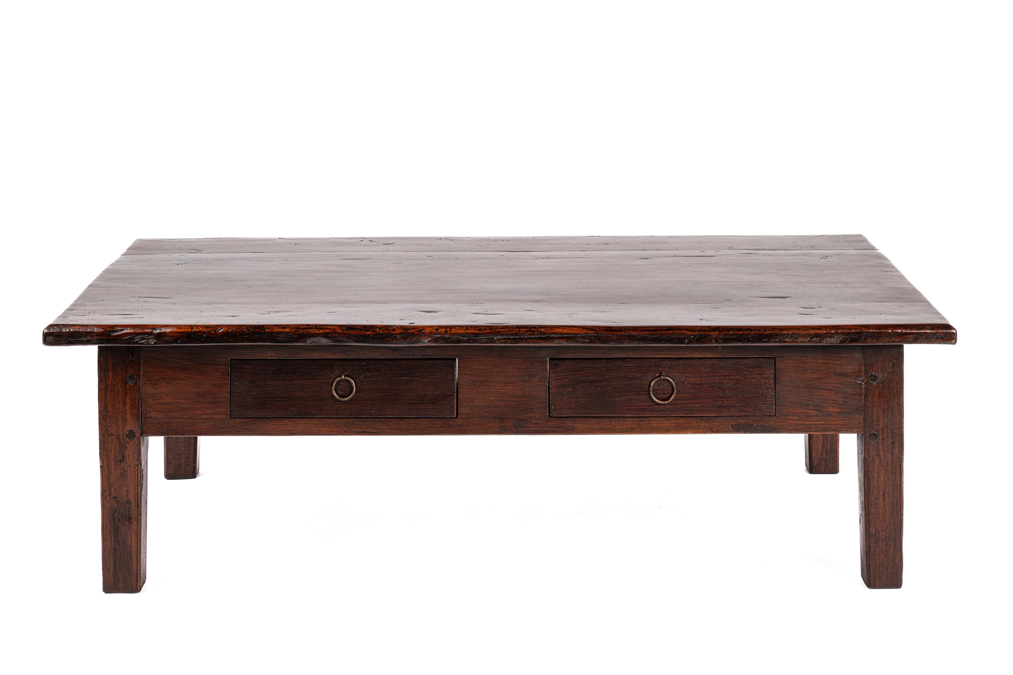 Cette superbe table basse est dotée d'un plateau en bois de teck massif d'une épaisseur de 1,2 pouce. Sous le plateau, un cadre élégant comprend deux tiroirs, chacun orné de poignées en acier forgé à la main. La table repose sur quatre pieds