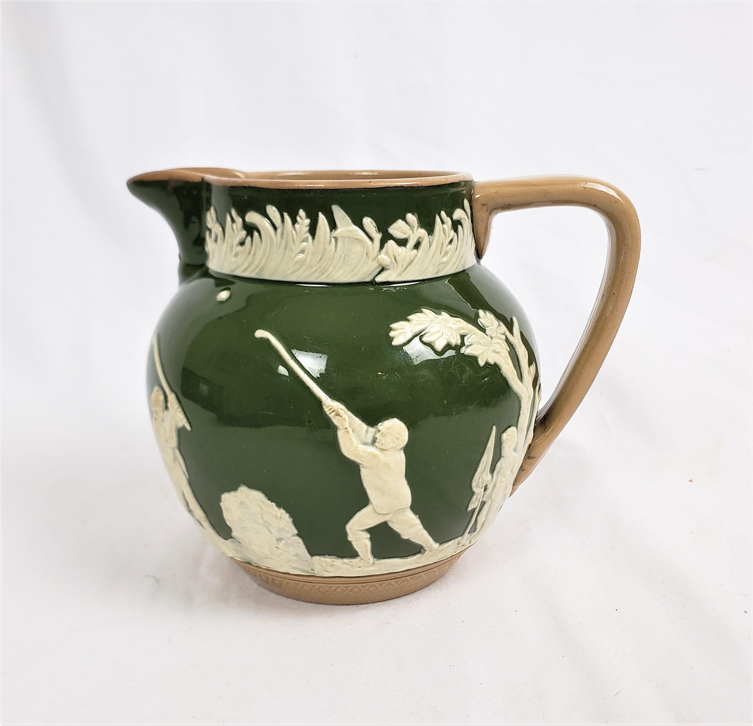 This antique pitcher was made by the well known Copeland Spode factory of England in approximately 1890 in the period Late Victorian style. This small pictcher is composed of pottery with a dark green ground and a series of golfing vignettes done in