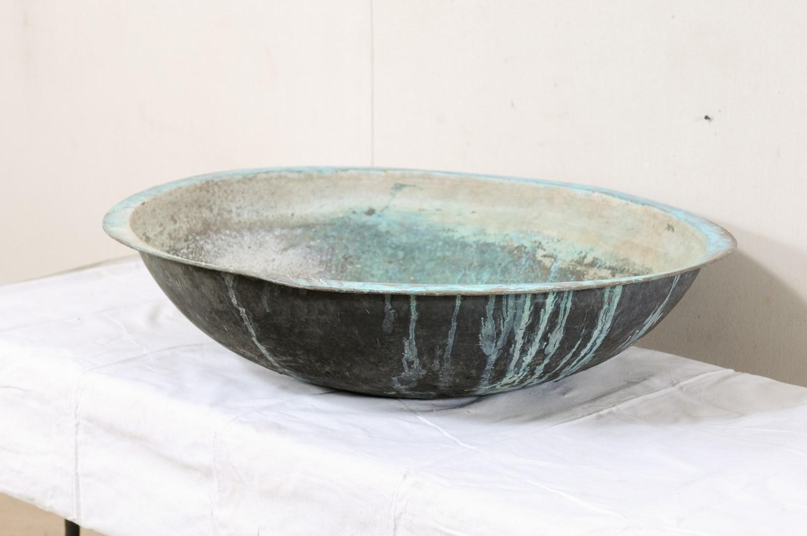 A Spanish large-sized copper bowl from the early 20th century. This antique copper bowl from Spain is nicely-sized at over 3 feet in diameter. The design is pure and simplistic, round-shaped with a flattened lip which extends slightly about the top