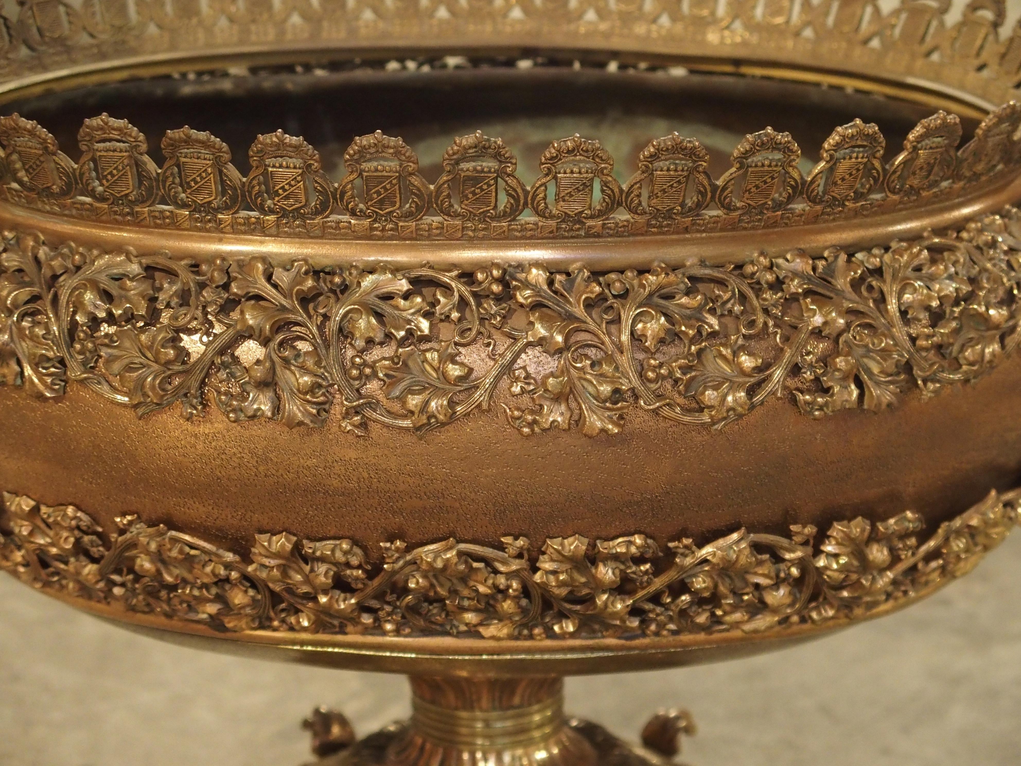 This highly detailed antique dragon coupe is composed of mixed metals, copper and bronze. The upper gallery rimming the top is composed of a series of shields with various motifs on and around them, but all the same design. Beneath this is a tiny