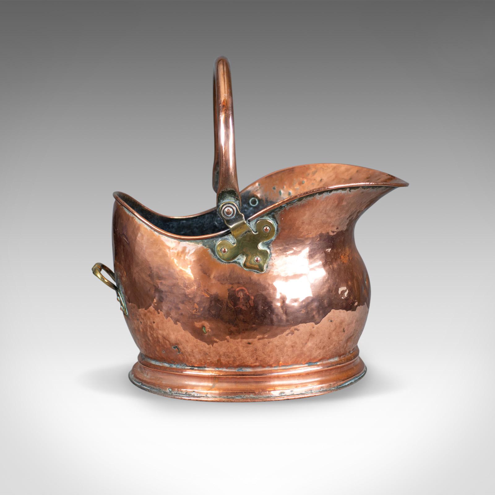 This is a vintage 1920s copper coal scuttle, an English, fireside bucket by Percy Metal Works, London and dating to 1929.

A pleasing mid-size fireside storage bin presented in good antique condition
of classic 'helmet' form and standing upon