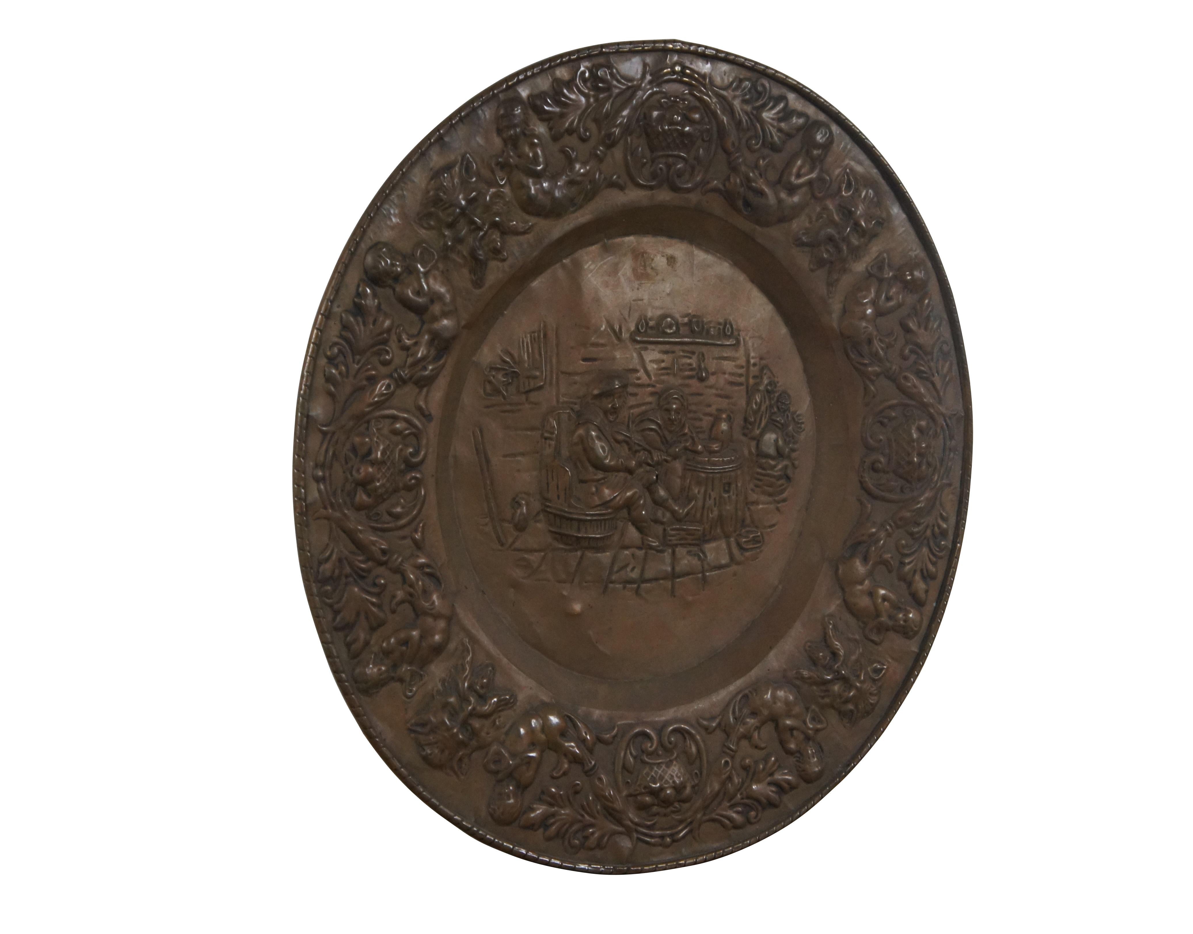 Antique embossed copper repousse wall hanging charger / platter featuring a tavern scene at the center and Neoclassical motif of cherubs / putties, baskets of fruit and Green Man faces around the edge.

Dimensions:
24.25
