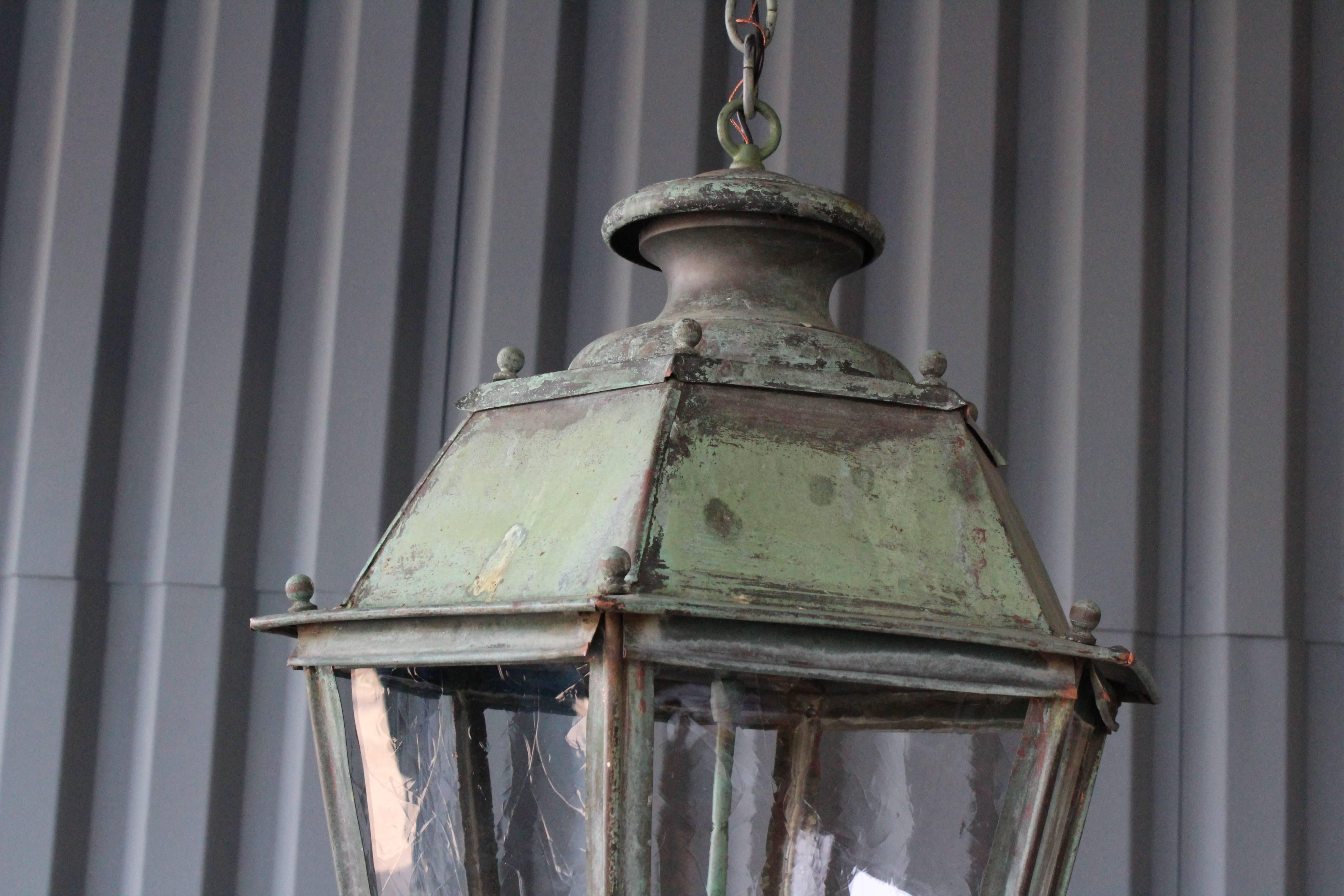 Antique hanging lantern with three lights in a beautifully aged copper patina. Features new glass panels and recently rewired with new wax candle covers.