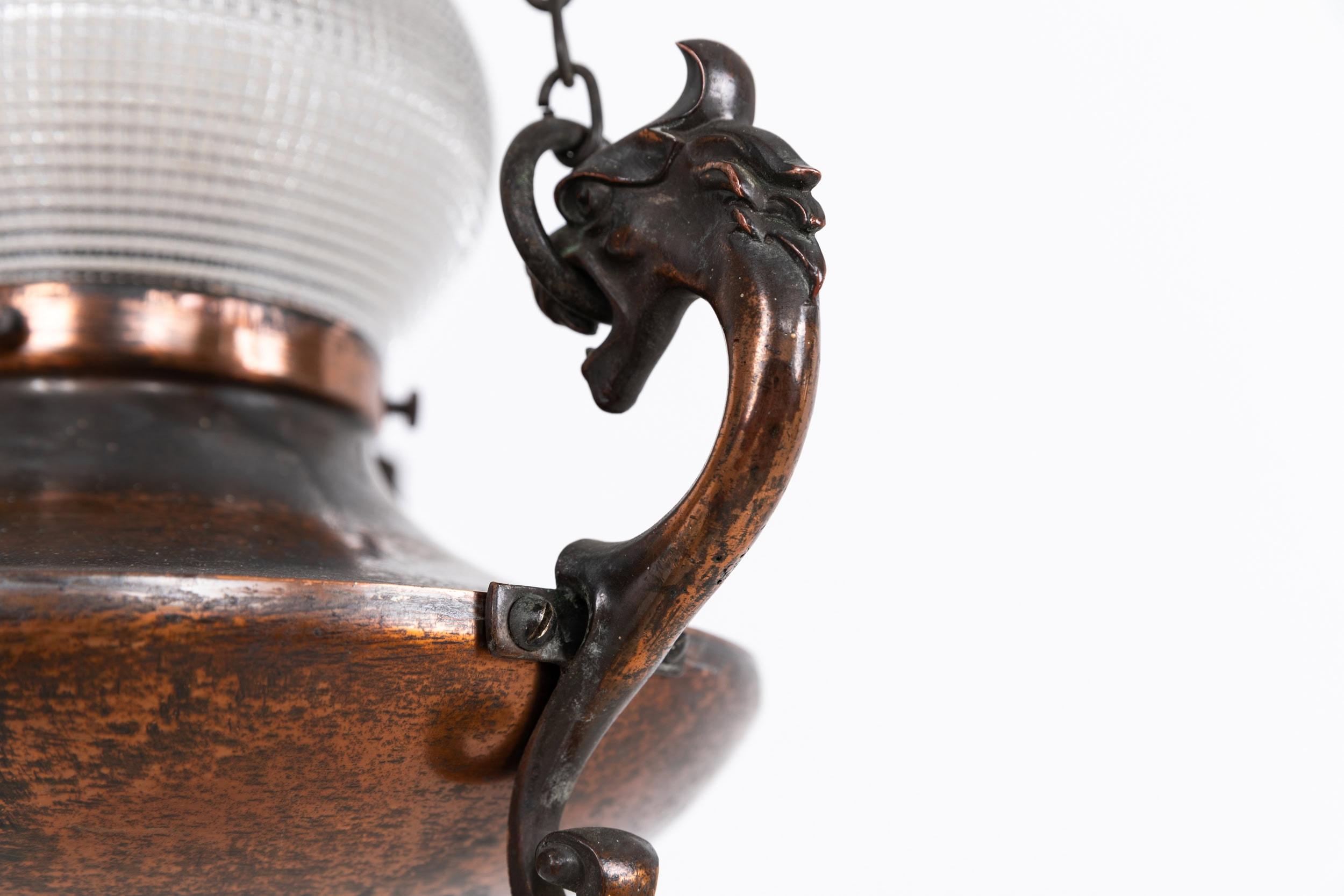 

An elegantly formed copper sanctuary light made in England. c.1920

Comprising of flashed copper metalwork which has beautifully patinated over time with cast hooks in the form of dragons heads. Holophane acorn glass shade stamped to tip.

Rewired
