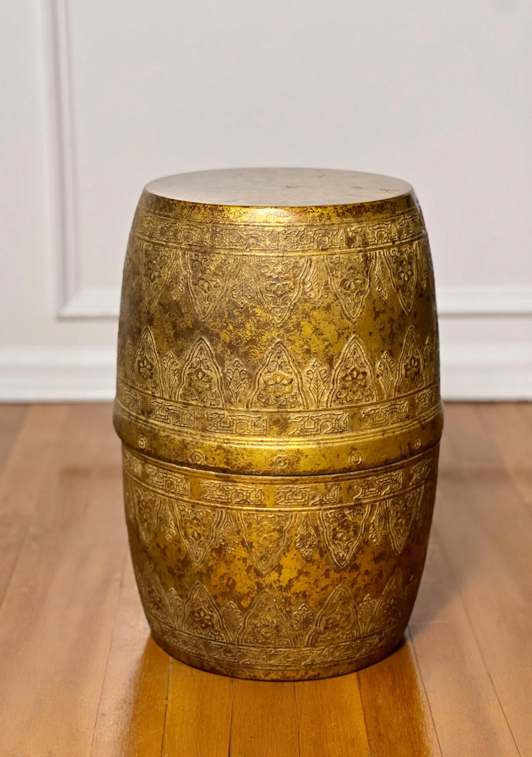 Table tambour marocaine ancienne en cuivre patiné avec décoration gravée à la main.  Il présente une forme cylindrique avec des motifs de volutes mauresques complexes et affiche une patine d'usage.  Une pièce chic et distinctive avec un objectif et