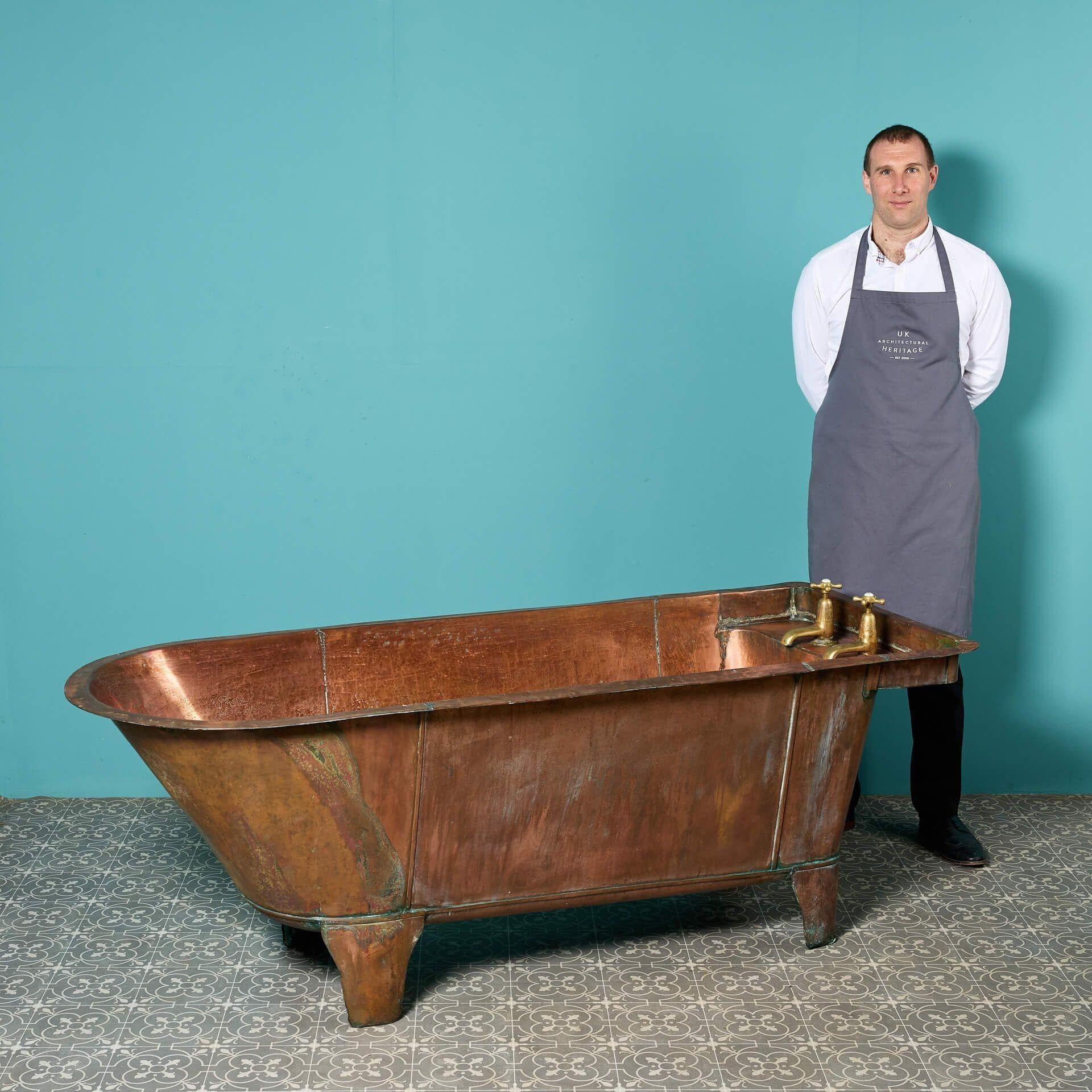 An antique copper roll top bathtub marked with the date 1889.

This copper bath features decorative copper feet, two large brass taps, and a practical yet aesthetic shelf area, complimented by an attractive timeworn look.

While baths like these are