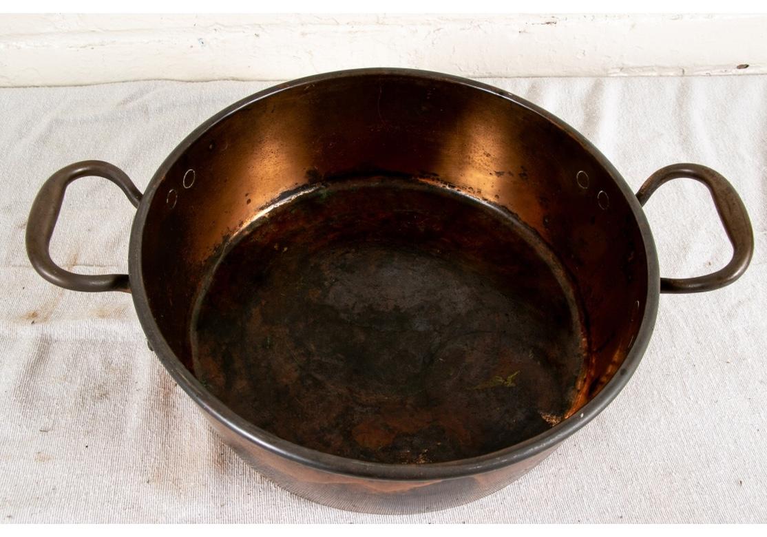 A large antique copper two-handled pot in all original condition with good weight and presenting very well. A shallow round pot, unlined, with twin handles. 
Measures: Diameter 13 3/4