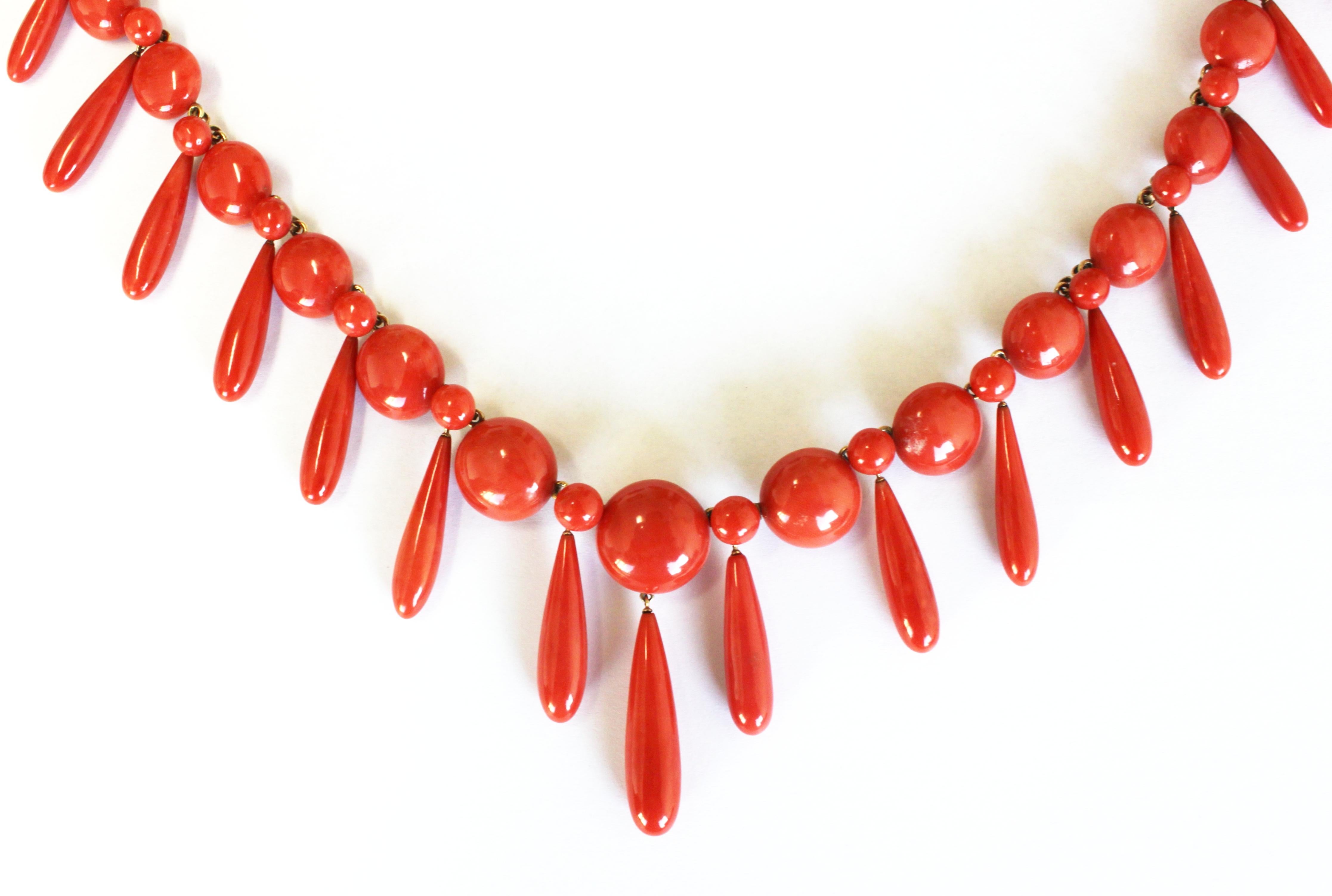 A rare antique set of a necklace and earrings set with graduating coral buttons and drops, ca. 1900. The Sardinian precious red coral in this set has a very nice and even colour, with the biggest button having a diameter of 17 mm and the biggest