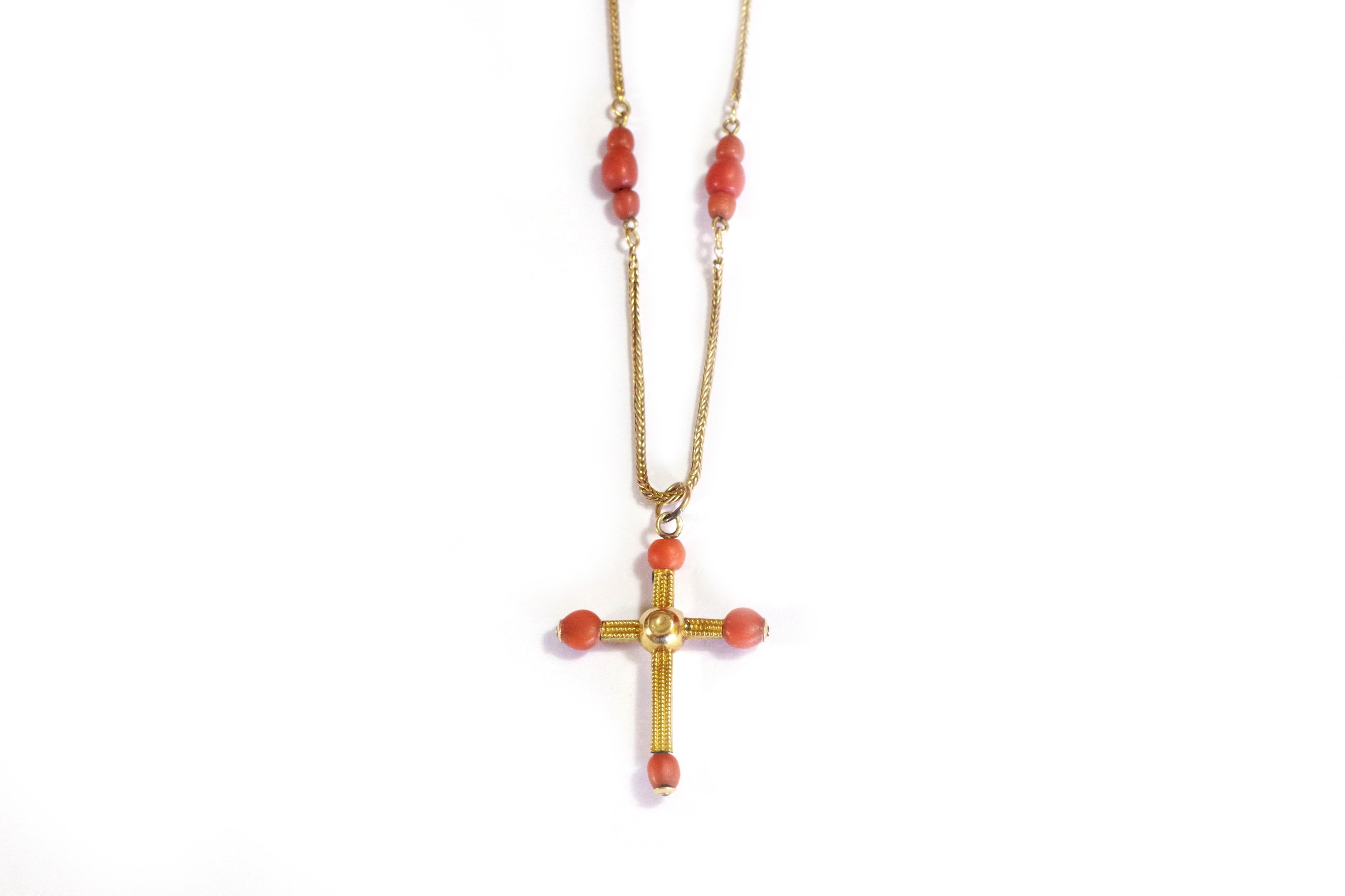 Antique coral cross gold necklace in yellow gold 18 karat. The necklace and its pendant are decorated with coral beads. Each trio of pearls is linked by delicate braided gold chains. The cross is decorated with a millegrain pattern and with a coral