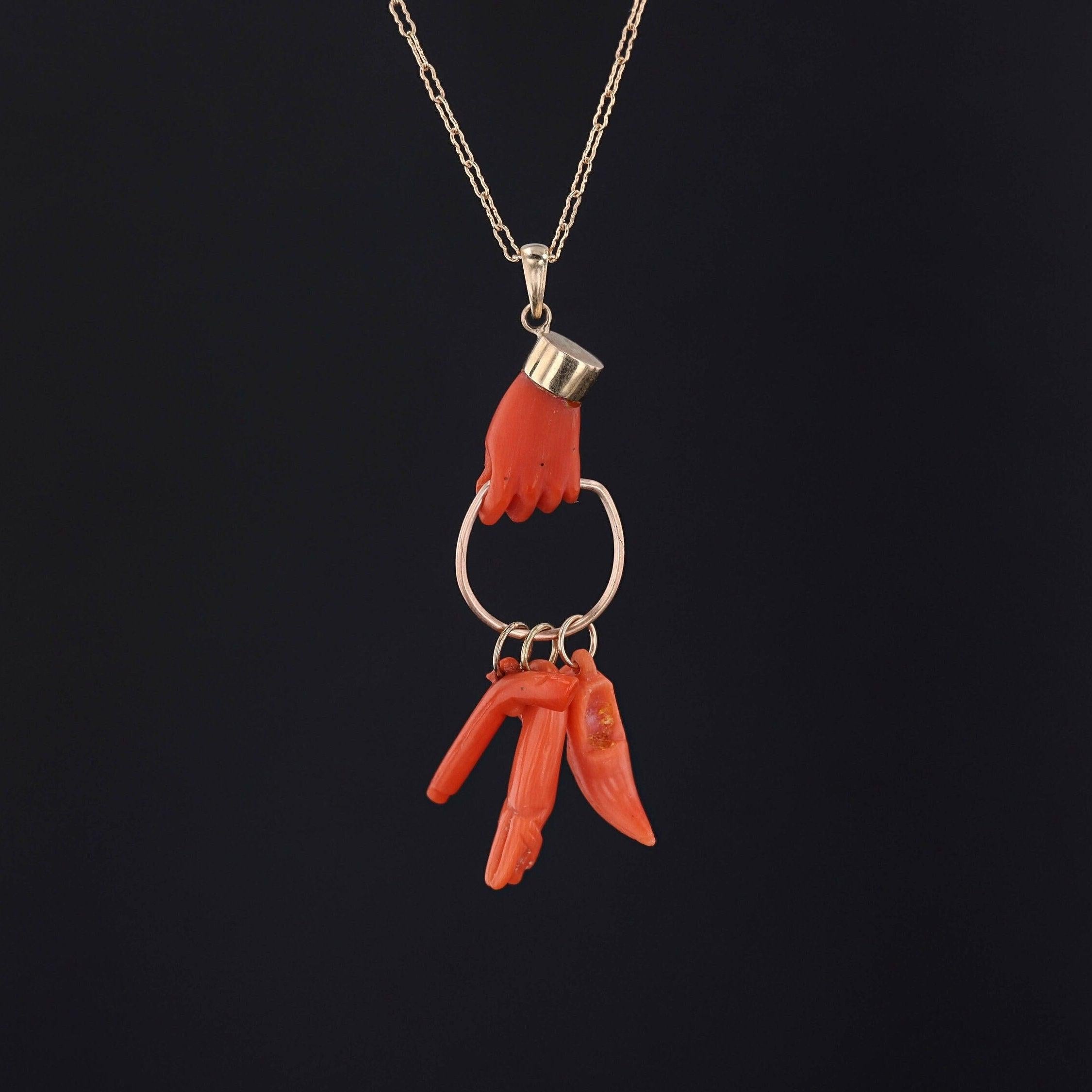 Pendentif ancien en or 14k (vers 1880) avec des charmes en corail représentant une chaussure, un chien et un revolver. L'attache en or 14k est un ajout ultérieur à la pièce.

Le pendentif mesure 2,3 pouces du haut de la bague au bas par 0,6 pouces