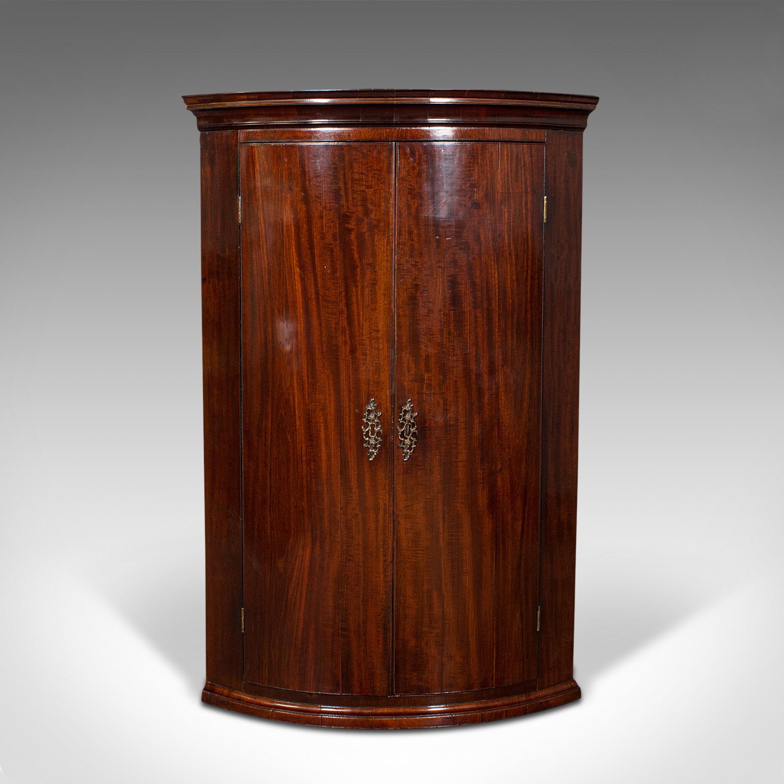 This is an antique corner cabinet. An English, mahogany bow front hanging cupboard, dating to the Georgian period, circa 1780.

Presents beautifully with delightful bow front form
Displays a desirable aged patina and in good order
Select stocks
