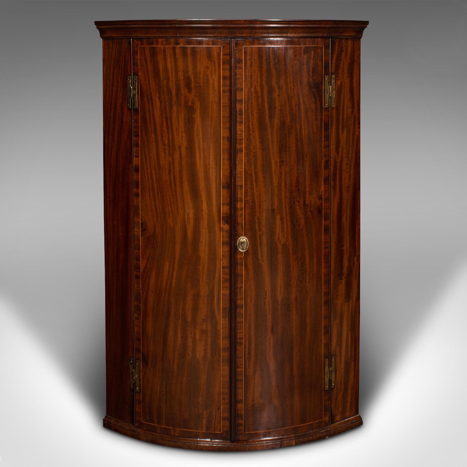 This is an antique corner cabinet. An English, mahogany and oak bow front wall cupboard, dating to the Georgian period, circa 1780.

A fine example of Georgian craftsmanship, with delightful figuring
Displays a desirable aged patina and in good
