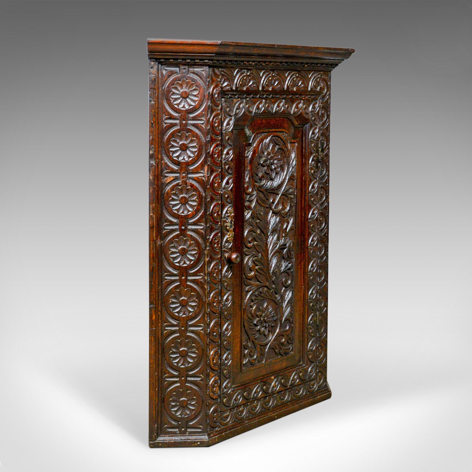 This is an antique corner cabinet. An English, Georgian, carved oak, hanging corner cupboard dating to the mid-18th century, circa 1760.

Crafted in English oak with good color
Desirable aged patina with a wax polished finish
Profusely carved