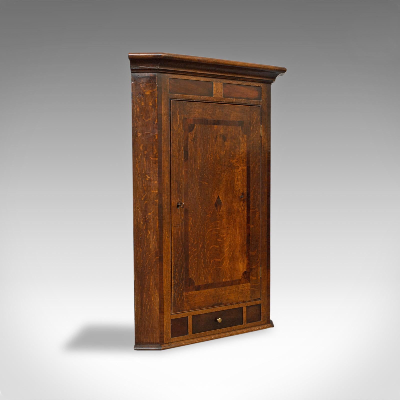 This is an antique corner cabinet. An English, Georgian, oak, hanging wall cupboard dating to the late 18th century, circa 1780.

Select cuts of oak display fine grain interest and wisps of medullary rays
Highlighted with panels of well figured,