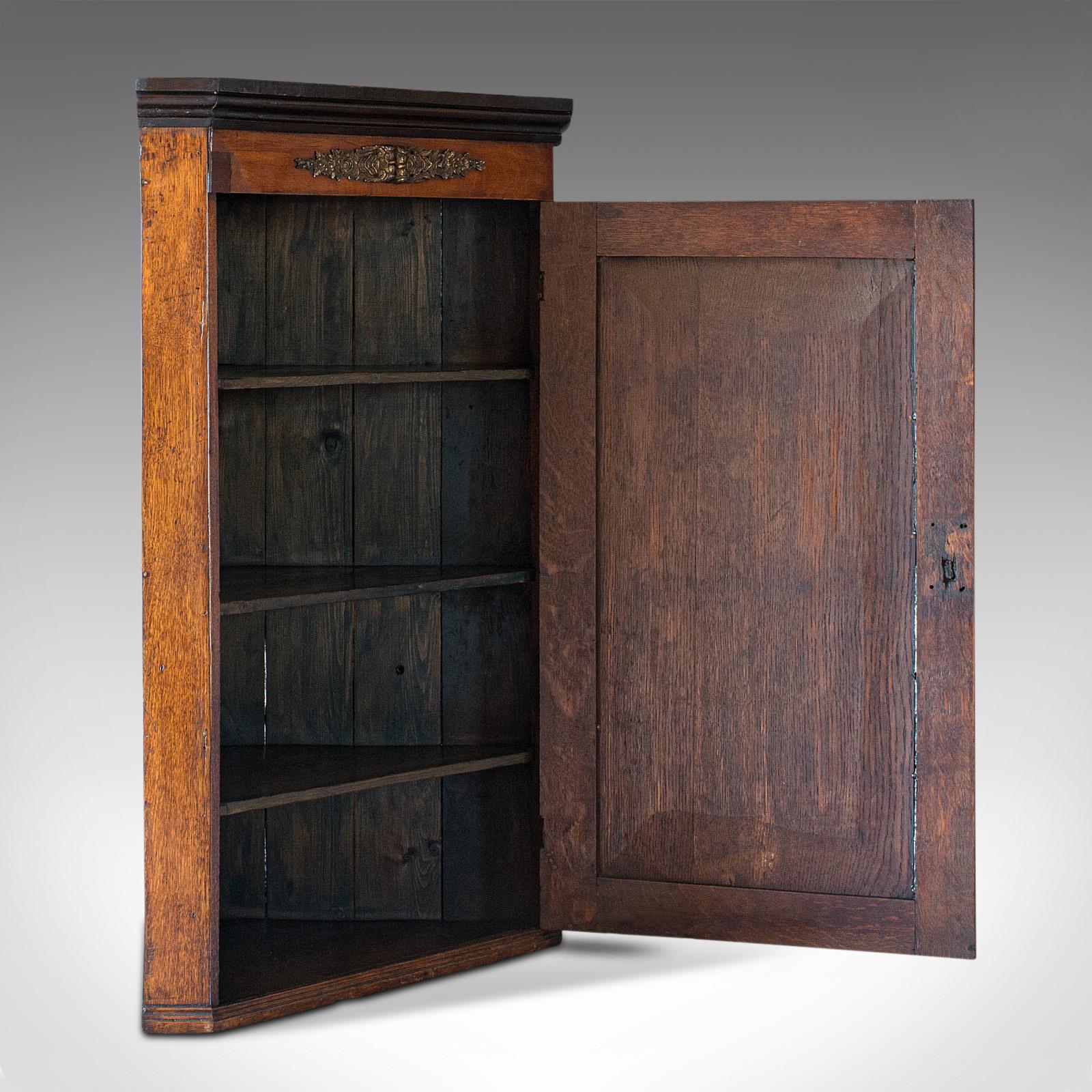 This is an antique corner cabinet. An English, oak and mahogany Georgian hanging cupboard, dating to the late 18th century, circa 1800.

Rich colour and grain interest abound
Displays a desirable aged patina
Shows fine grain interest and wisps