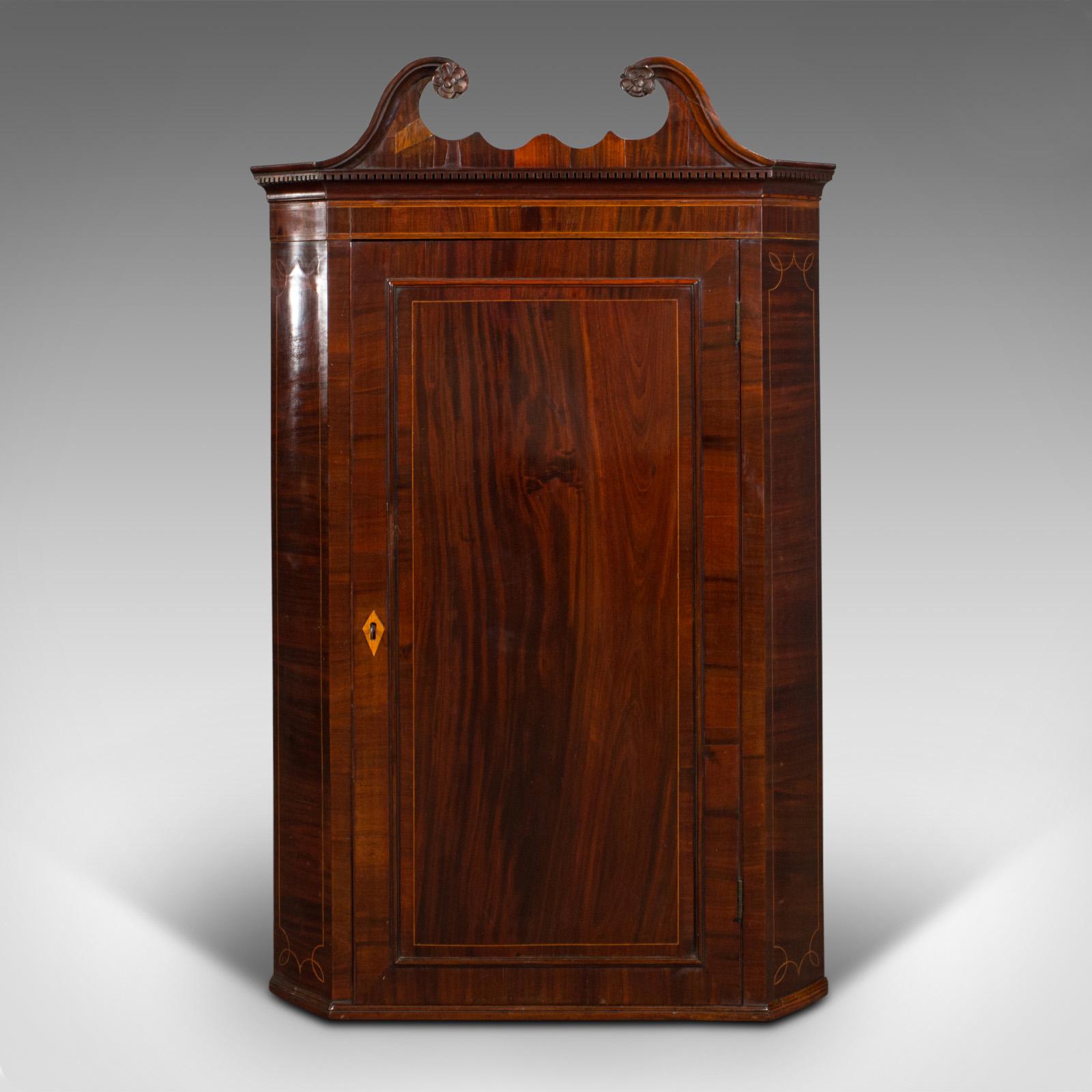 This is an antique corner cabinet. An English flame mahogany and boxwood inlaid wall cupboard, dating to the Georgian period, circa 1760.

Distinctive corner cupboard graced with fine figuring and colour
Displays a desirable aged patina and in
