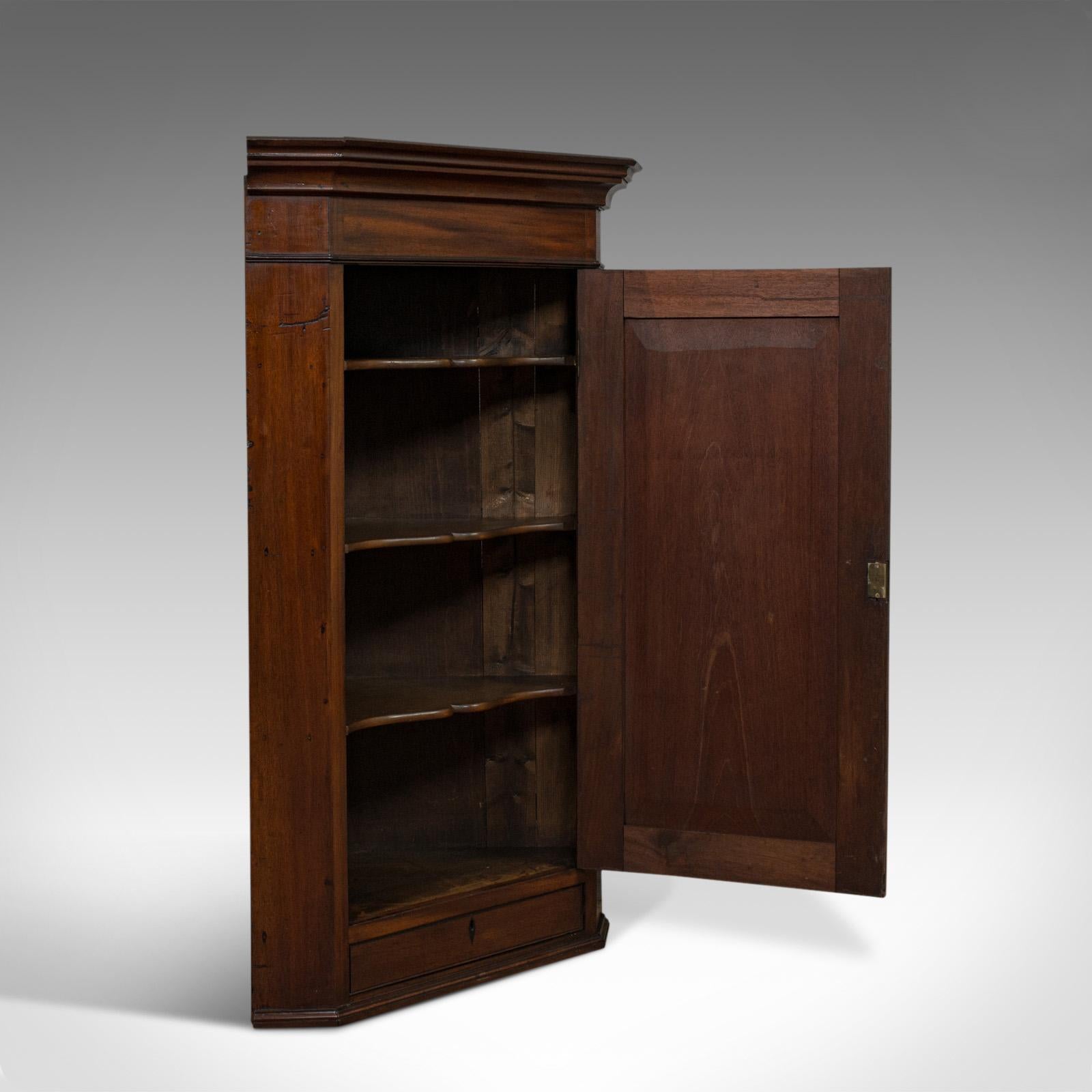 This is an antique corner cabinet. An English, walnut and mahogany, wall-hanging cupboard dating to the Georgian period at the turn of the 19th century, circa 1800.

Classic Georgian form and appeal
Displays a desirable aged patina
Select walnut