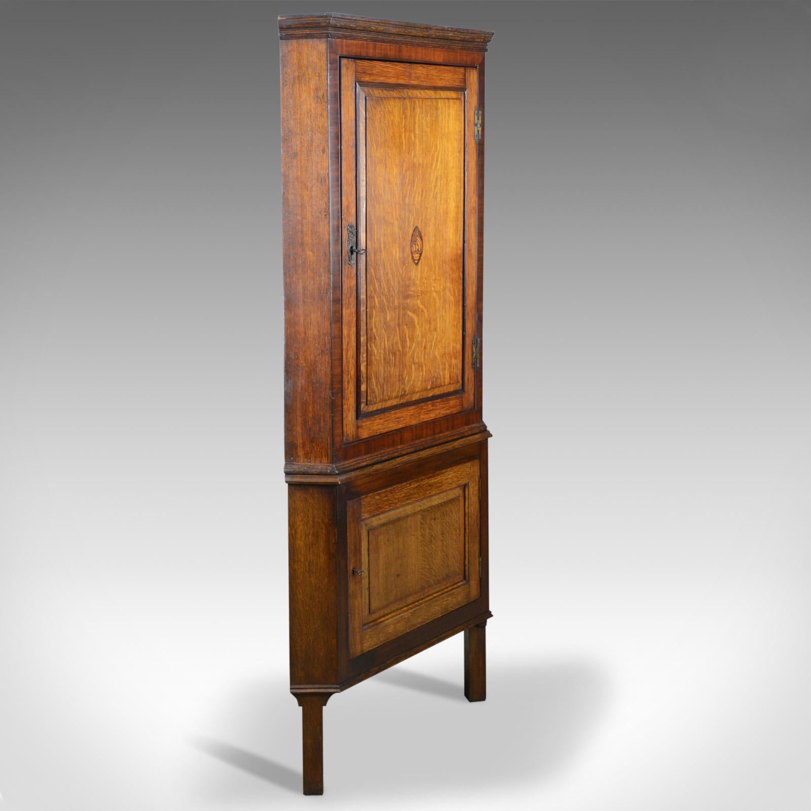 This is an antique corner cabinet on stand, an English, George III, oak and mahogany cupboard on Victorian panel cupboard stand, dating to circa 1770 and later.

Attractive honey hues to the English oak
Crossbanded in mahogany to the