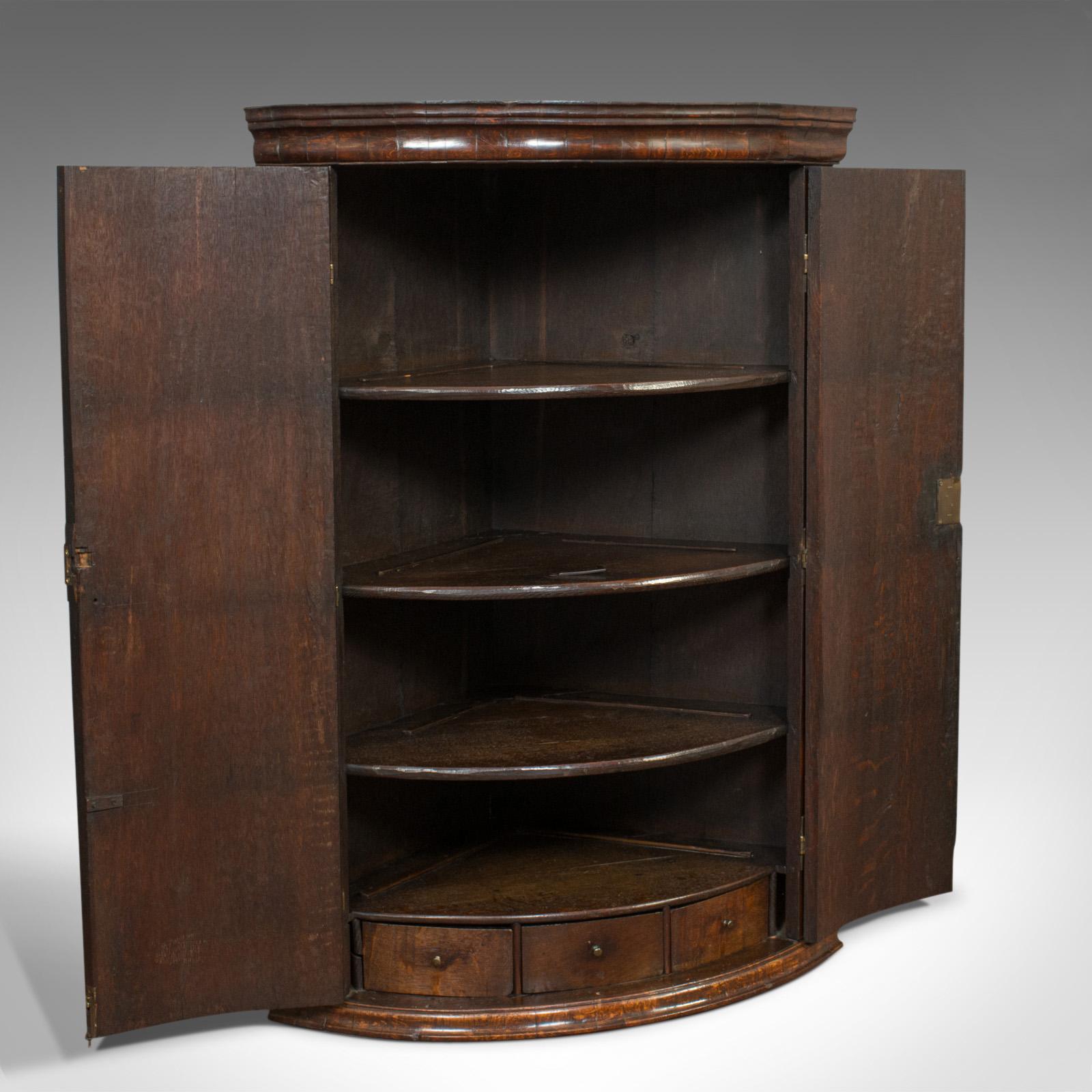 This is an antique corner cupboard. An English, oak bow front hanging cabinet dating to the Georgian period of the 18th century, circa 1760.

A splendid Georgian cabinet
Displays a desirable aged patina
Striking book-matched oak shows fine grain
