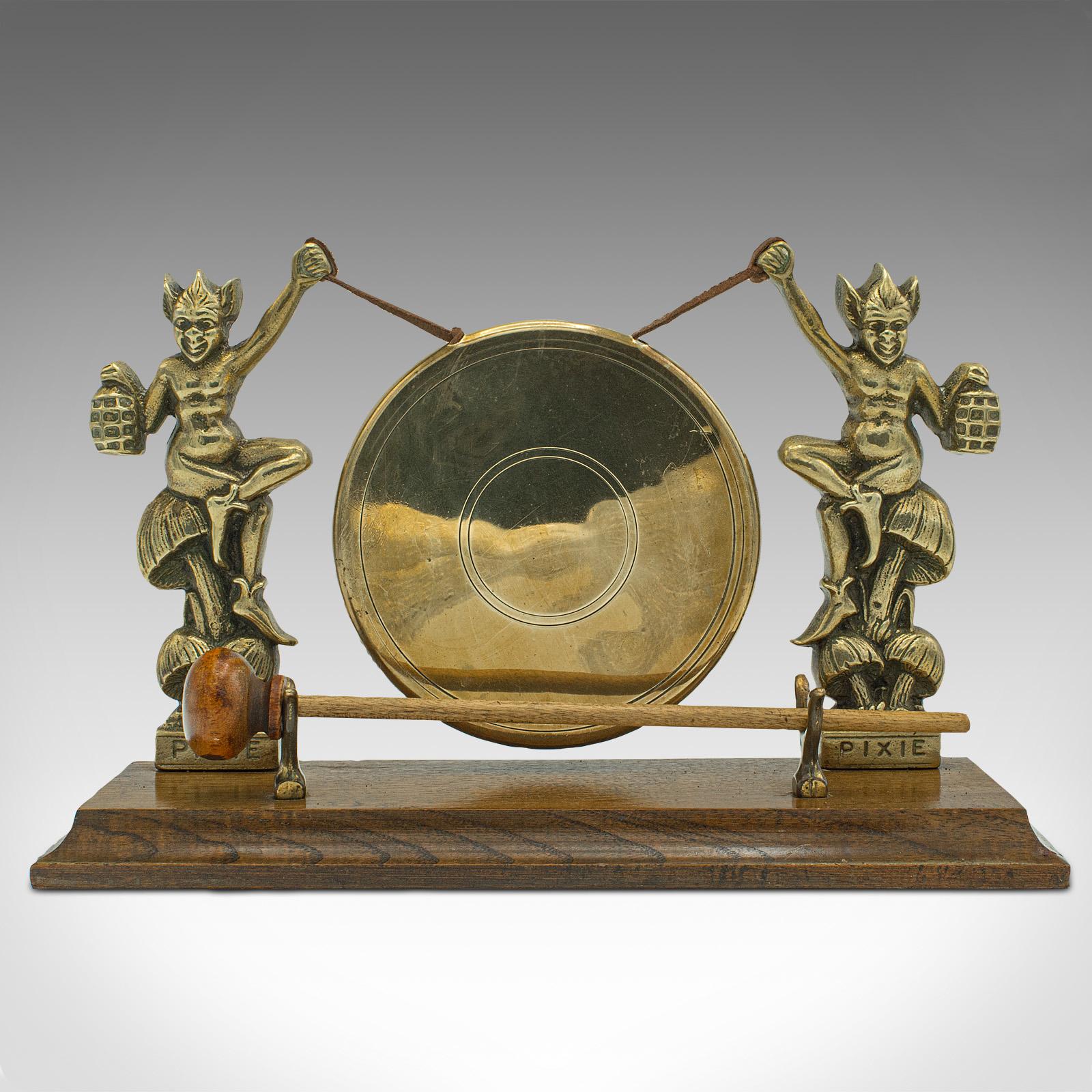 This is an antique Cornish Pixie gong. An English, brass and oak dinner chime, dating to the late Victorian period, circa 1900.

Charming gong raised by iconic Cornish Pixie figures
Displays a desirable aged patina and in good order
Polished