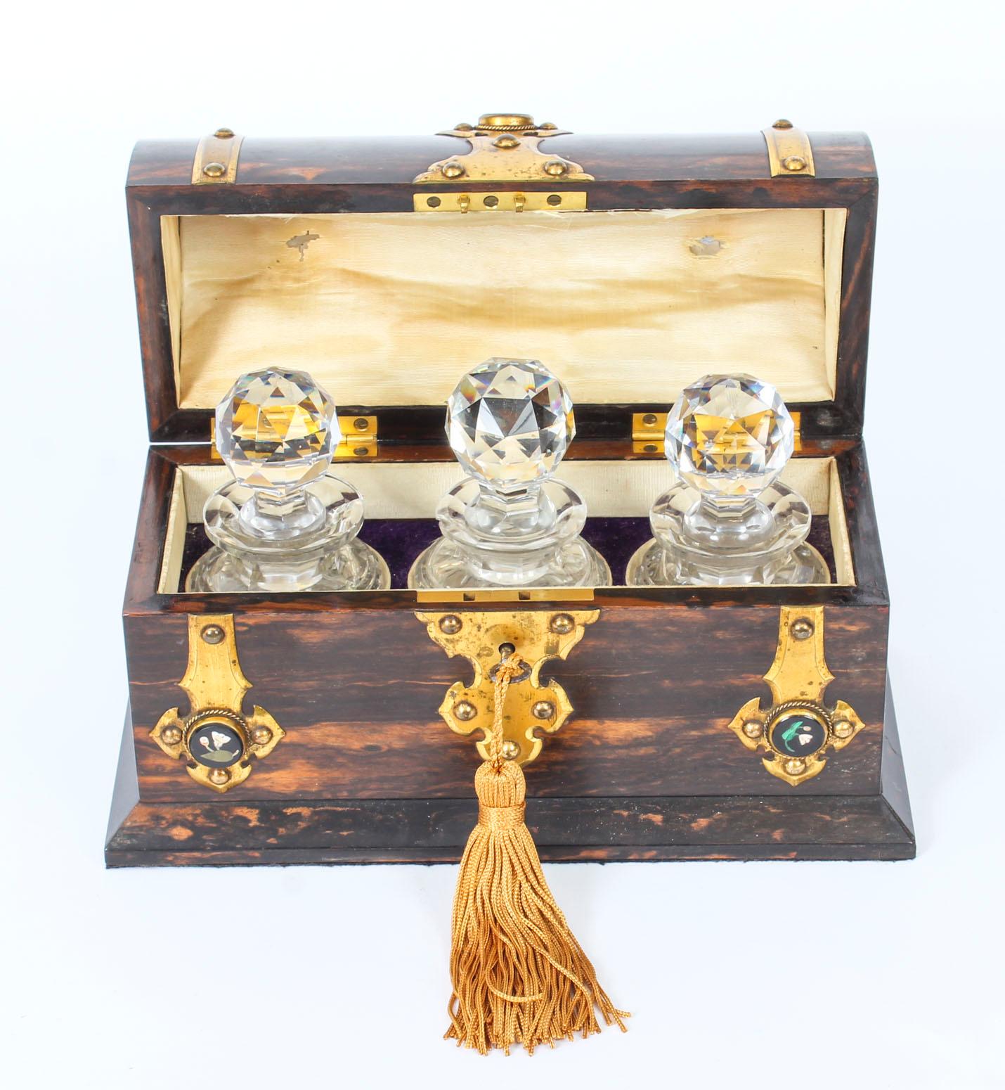Es handelt sich um eine antike viktorianische Coromandel-Duftflaschendose in gewölbter Form mit aufwändigen dekorativen Messingbeschlägen mit eingelassenen attraktiven Pietra Dura-Cabochons, datiert um 1860.

Der gewölbte Deckel zeigt drei