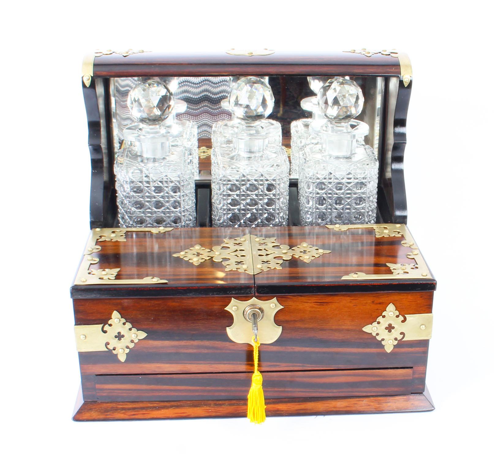 This is a superb antique Victorian coromandel cased three decanter tantalus and games compendium, circa 1880 in date.

It was skillfully crafted in rare coromandel with cut brass mounts, three cut crystal glass decanters with stoppers, a mirrored