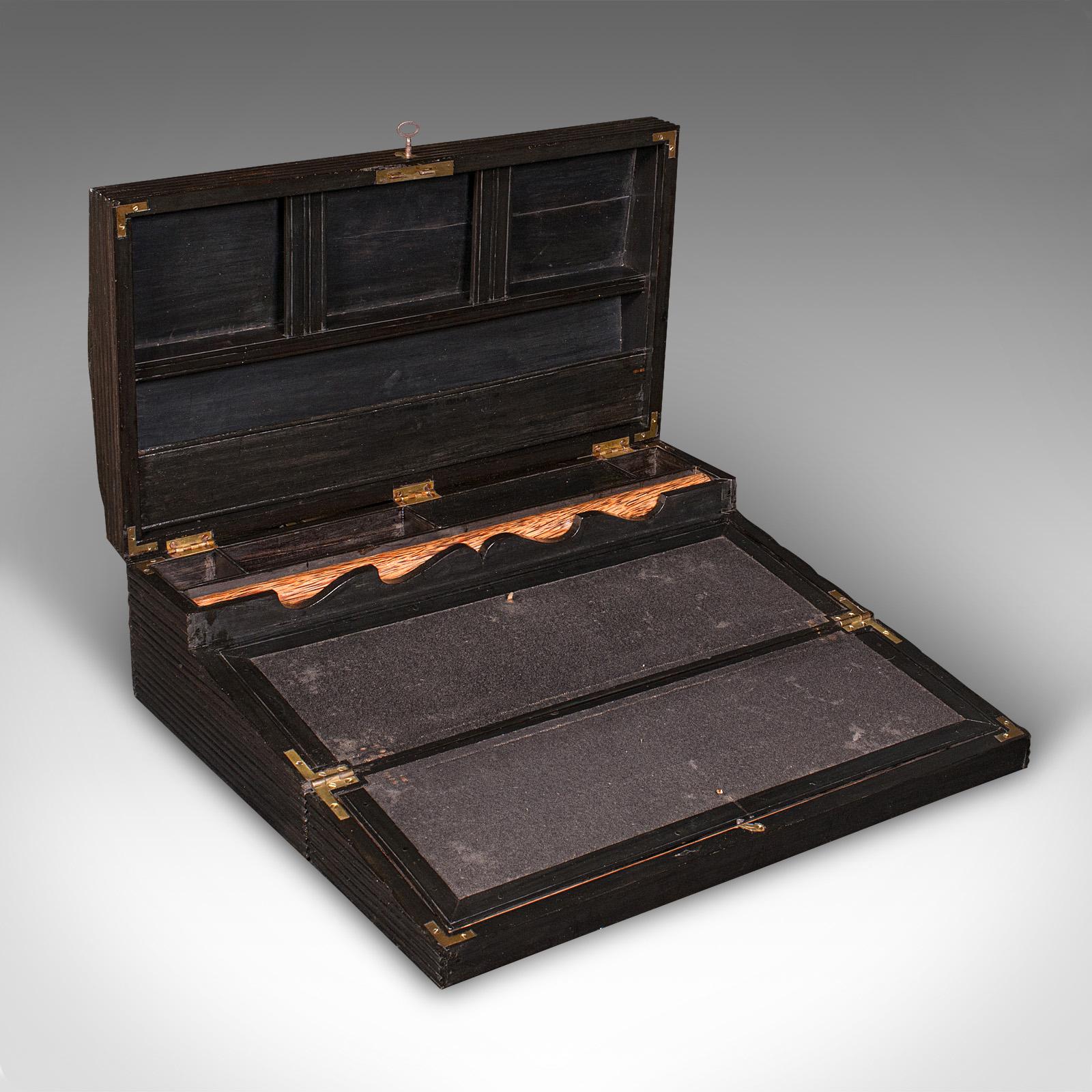 
This is an antique gentleman's correspondence box. A Ceylonese ebony campaign writing slope, dating to the early Victorian period, circa 1850.

Fascinating grooved finish, with a well appointed suite of features
Displays a desirable aged patina and