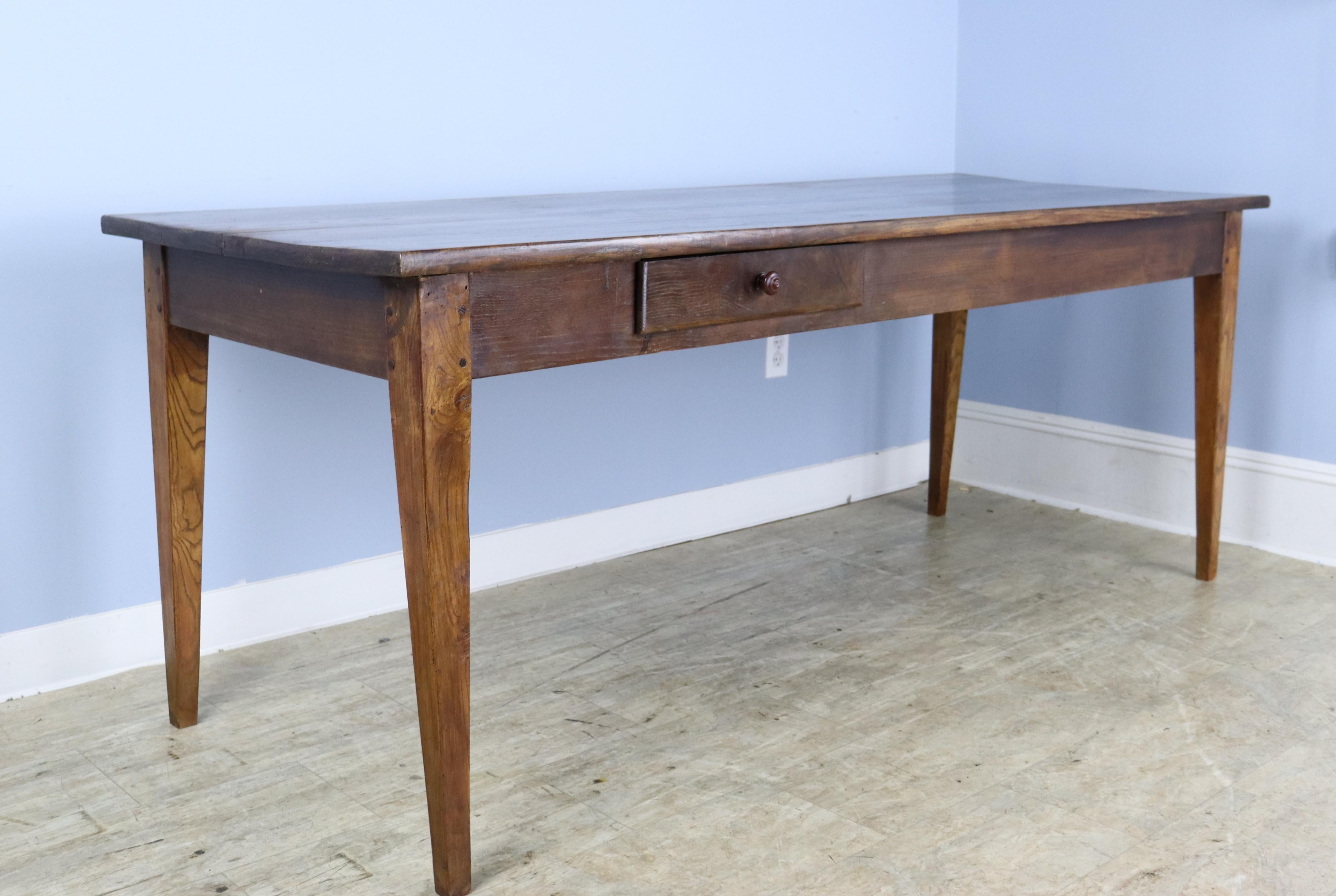 An elegant chestnut farm table with a single offset drawer and a useful bread slide. Well grained tapered legs, pegged at the apron. 24 inch apron height is good for knees and there are 70.5 inches between the legs on the long side. The top is in