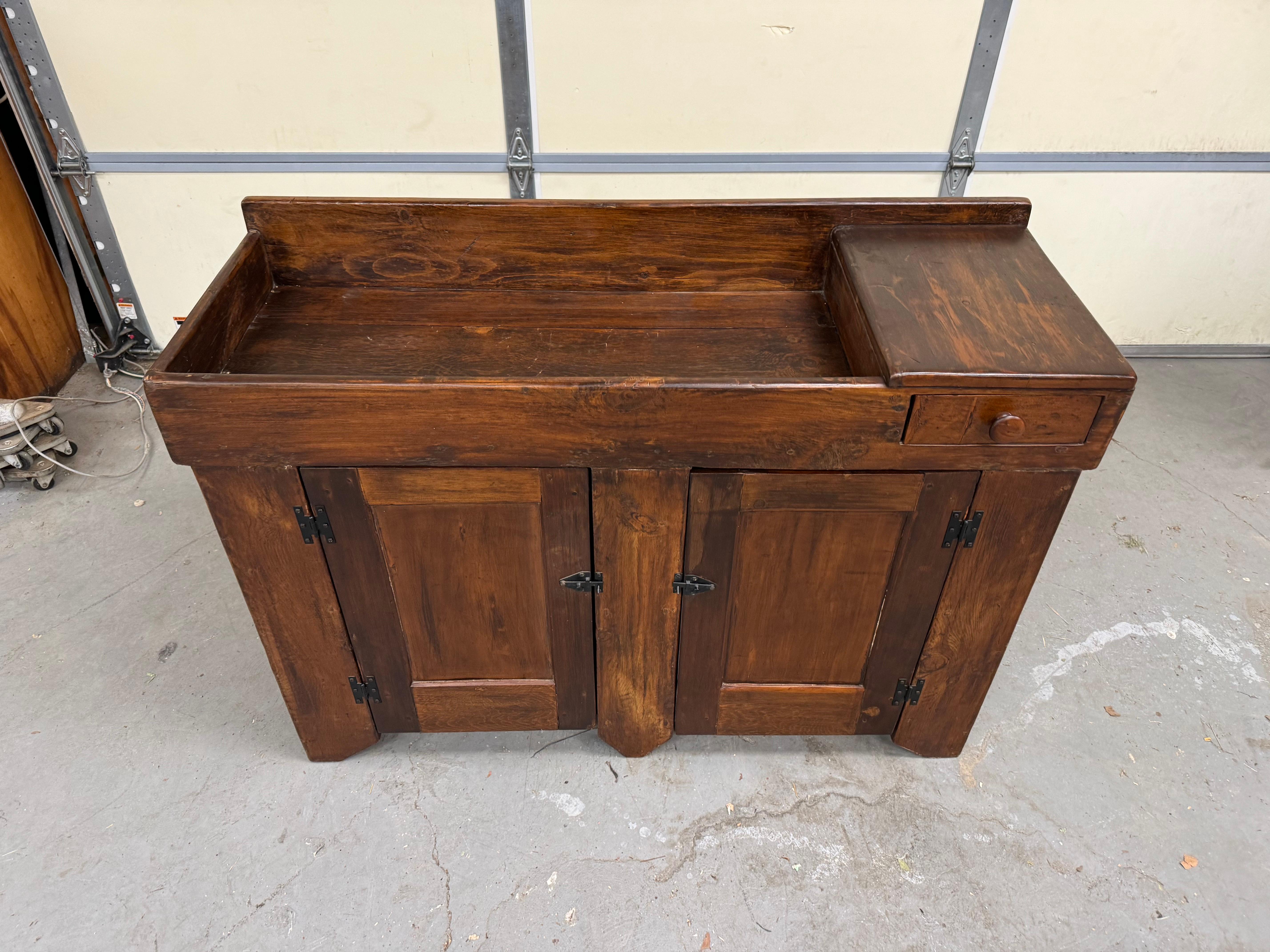 Offered is a solid Pine wood Antique Country Elongated Dry Sink. We estimate this to be from the early 1900's. It features 1 small drawer and 2 doors with loads of storage. Its design features the use of random boards in its construction. This dry