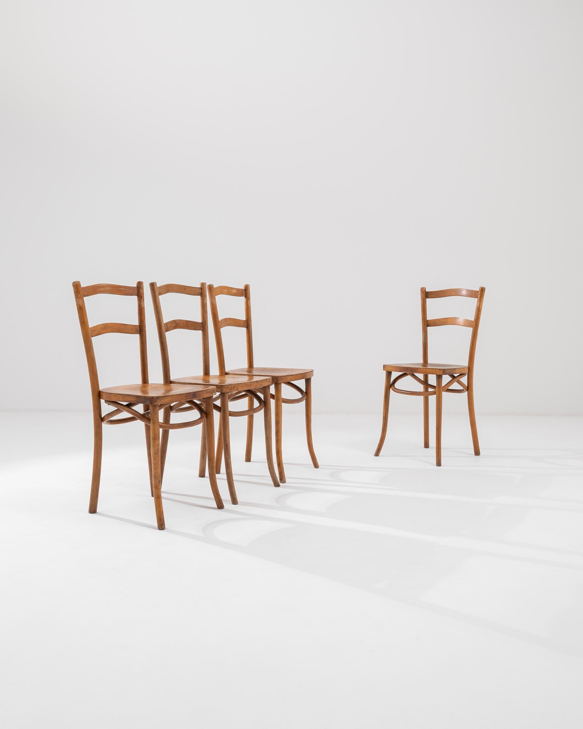 A set of wooden dining chairs created in 19th century France. Exuding an air of calm and elegance, this set of dining chairs gleam as a shining example of traditional french craftsmanship. Elegantly described scroll patterning decorates the seat of