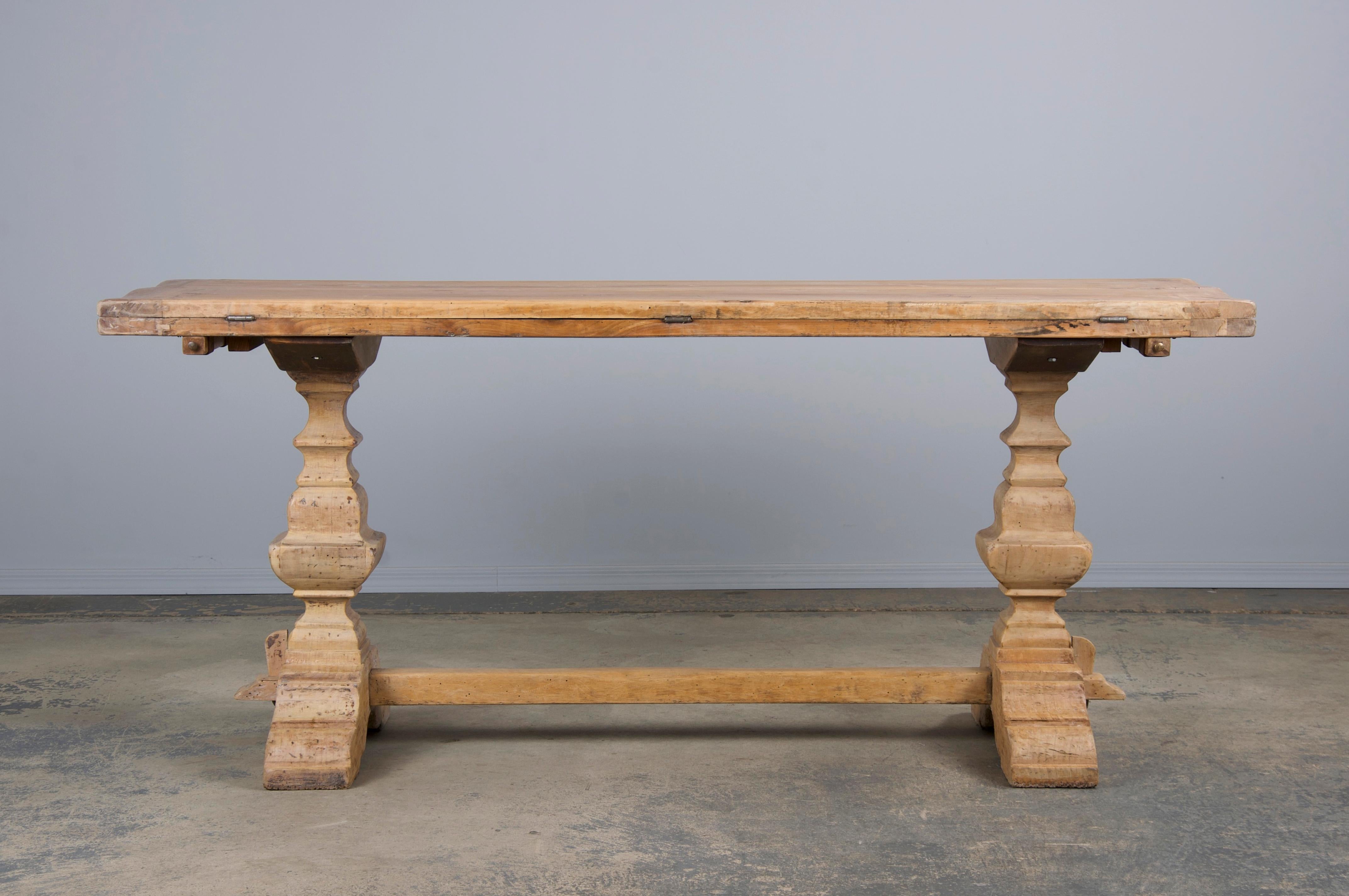 A 19th-century French farmhouse folding dining table or console, sourced from Provence, France. Hand-crafted from solid walnut, it features a naturally aged patina with a bleached finish. The table's narrow frame is topped by a 5'9