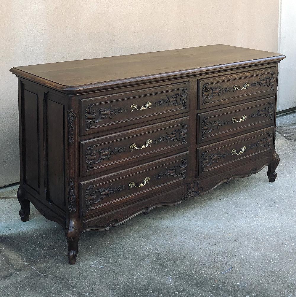 Antique country French double commode provides six drawers for capacious storage in style! handcrafted and carved from solid oak, it features double raised & recessed panels on each side, plus beautifully carved drawer facades and a scrolled apron