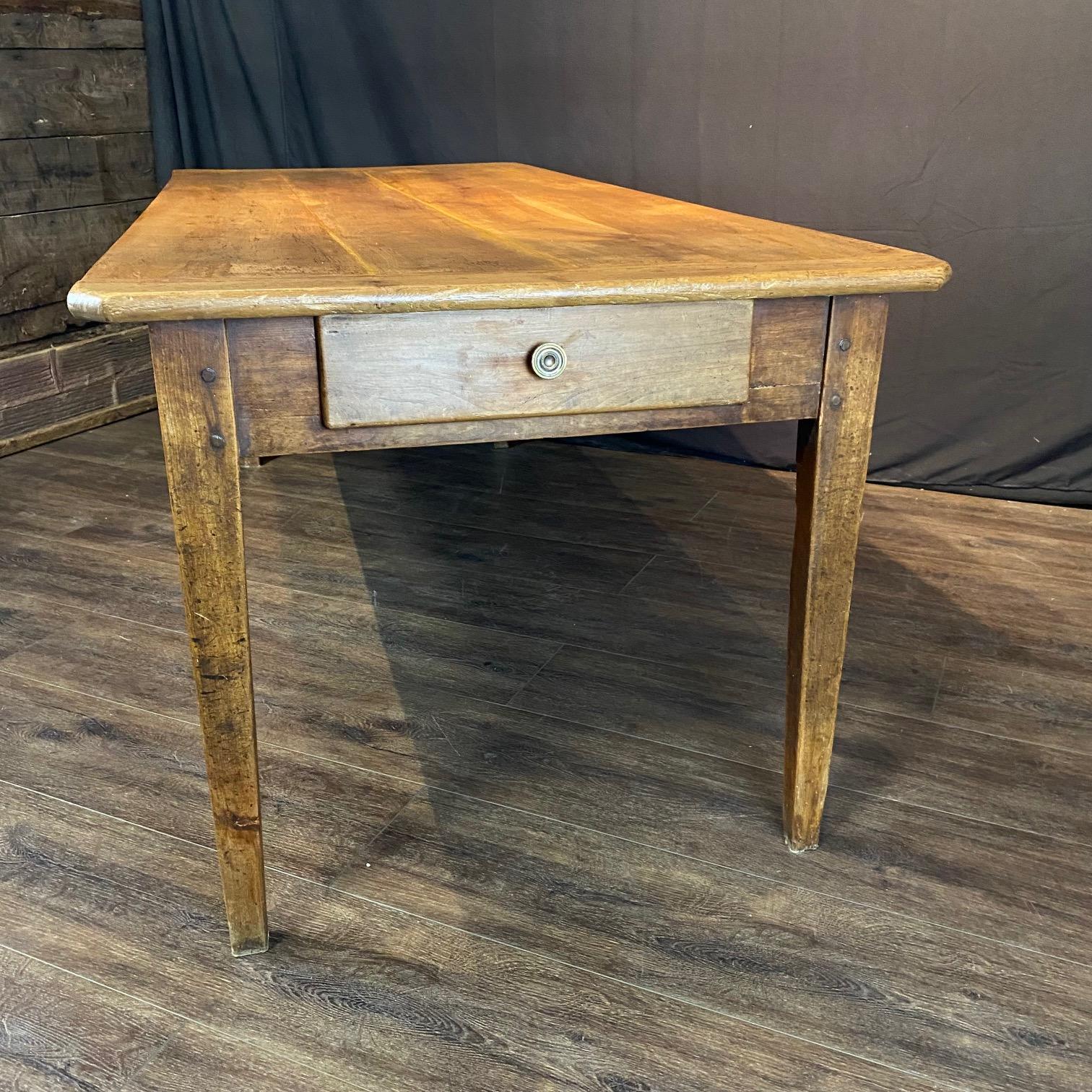 Classic 19th century country French provincial farmhouse dining table crafted from rich walnut. The ends are fitted with two storage drawers with gold knobs. The table is supported by elegant tapered legs, and the table top has lovely breadboard