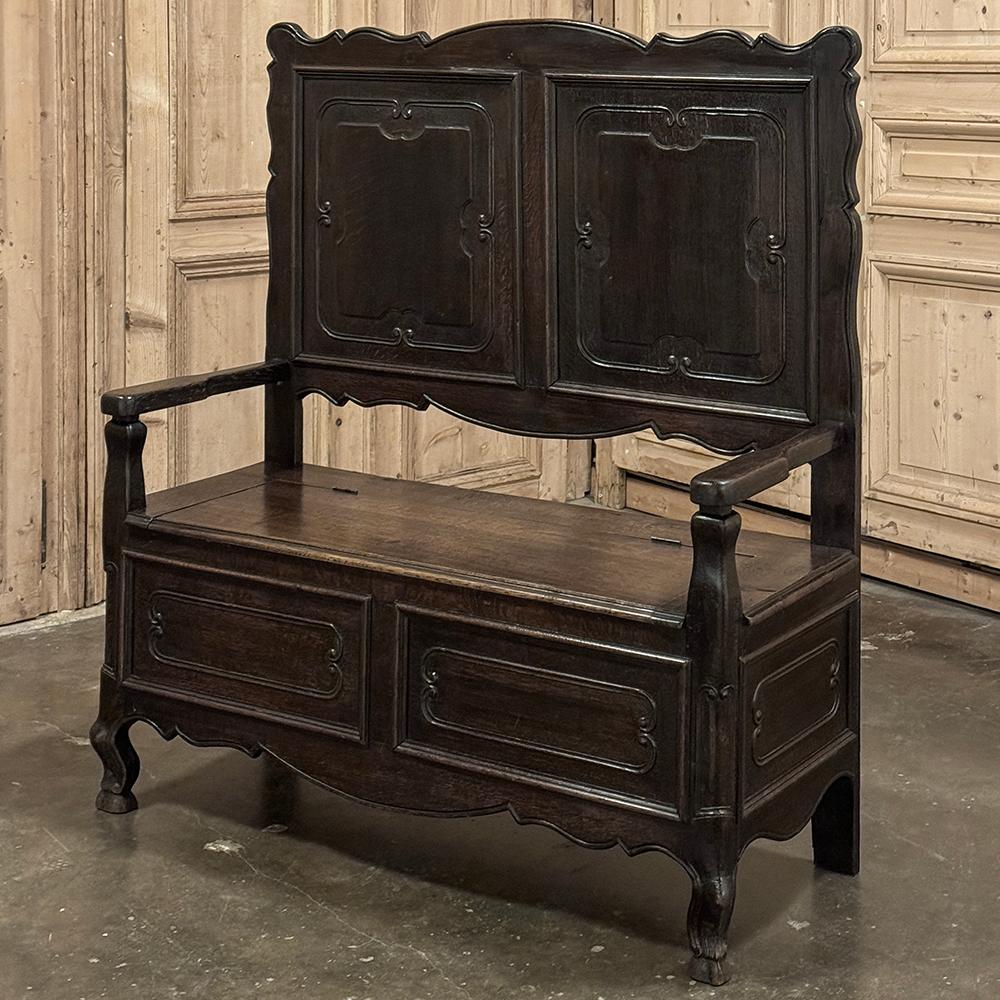 Antique Country French Hall Bench will add a touch of provincial flair to any room or hallway, plus the added convenience of a place to sit, and even a bit of storage under the seat, like a trunk!  Hand-crafted from solid oak, it features a scrolled