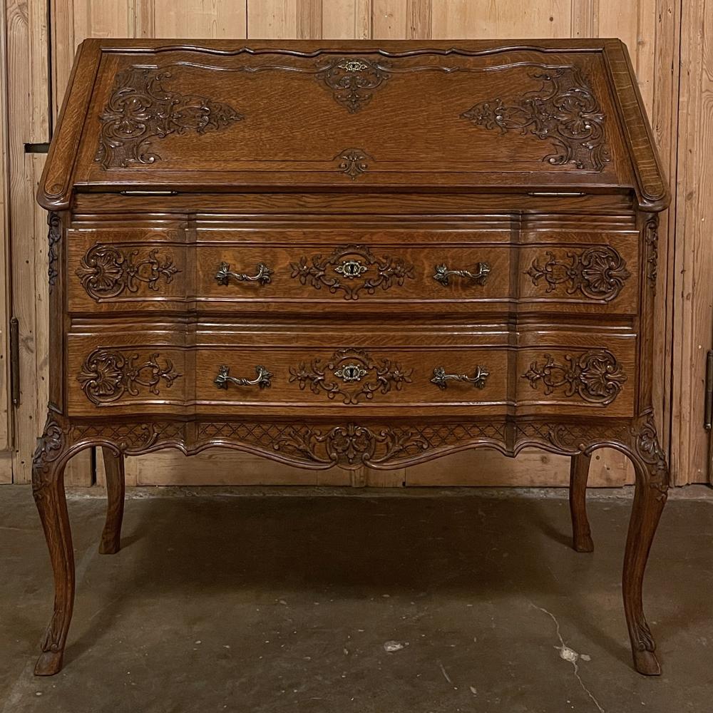 Antique Country French Liegoise Regence style secretary was hand-crafted from solid oak, and features a traditional slant-front drop down desk surface that when closed, exhibits extraordinary artistry carved directly into the sumptuous wood!