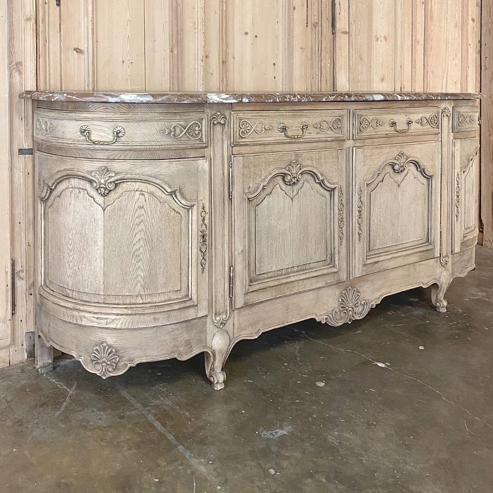 Antique country French Louis XV stripped oak marble top buffet represents the perfect blend between the opulent and casual! Gracefully scrolled panels dominate the facade, accented with carved shell motifs, emphasizing the rounded side design that