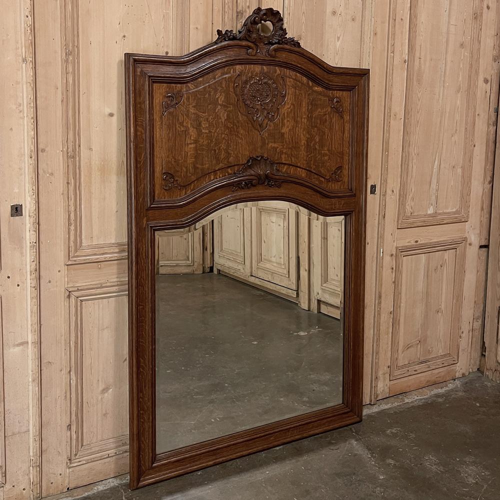 Antique Country French Louis XV Trumeau was sculpted from old-growth oak, and features a subtle rendition of the Rococo flair with a tailored overall effect. The gracefully arched crown features a beautifully sculpted asymmetrical shell, floral and