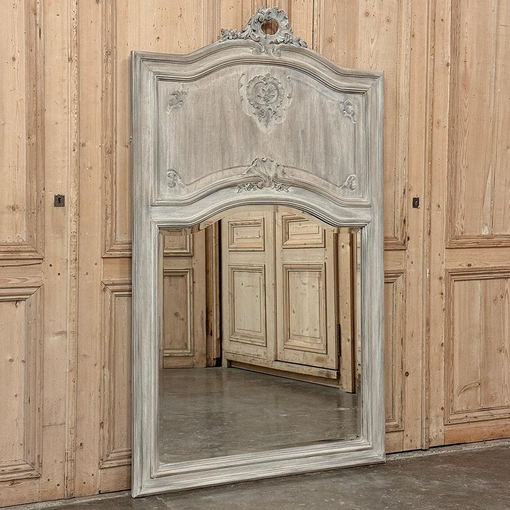 Le miroir Trumeau de style Louis XV lavé à la chaux a été sculpté dans du chêne ancien et présente une subtile interprétation du style rococo avec un effet d'ensemble sur mesure.  La couronne gracieusement cintrée est ornée d'une coquille