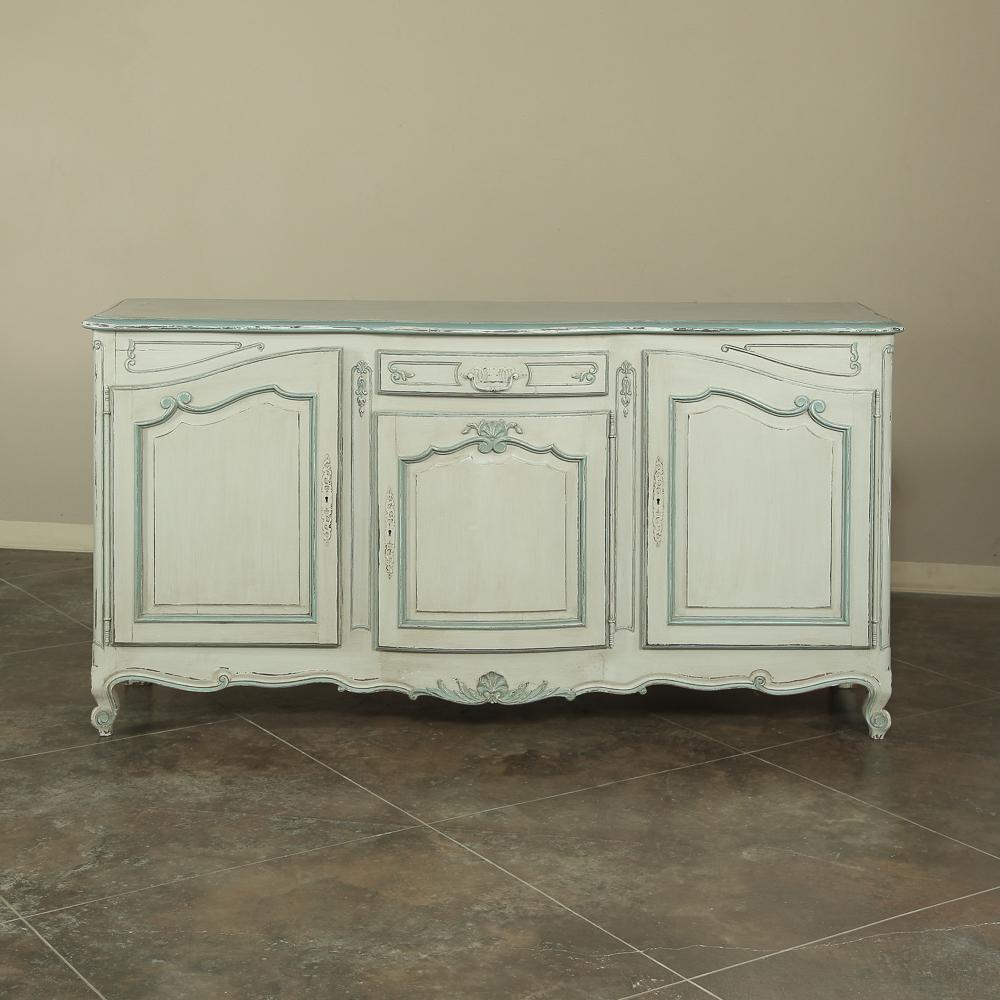Featuring unmistakable Country French lines yet rendered with a relative simplicity, this charming antique Country French painted buffet boasts a patinated painted finish. Called a trios porte enfilade in France, this antique furniture example