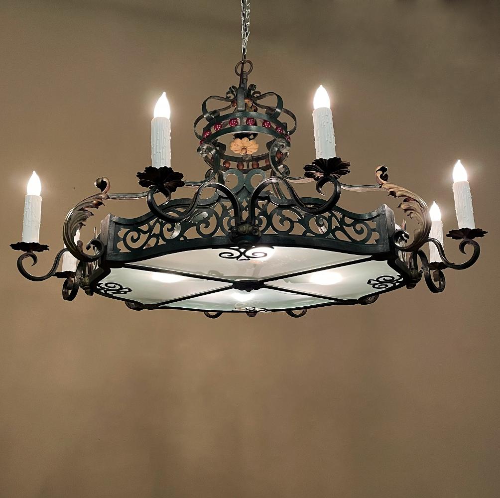 Ce lustre ancien en fer forgé peint à la française est un magnifique exemple d'élégance et de savoir-faire dans les meilleures traditions ! Le cadre ovale profilé sert de base au design, avec des volutes ouvertes sur tout le périmètre, et sur lequel