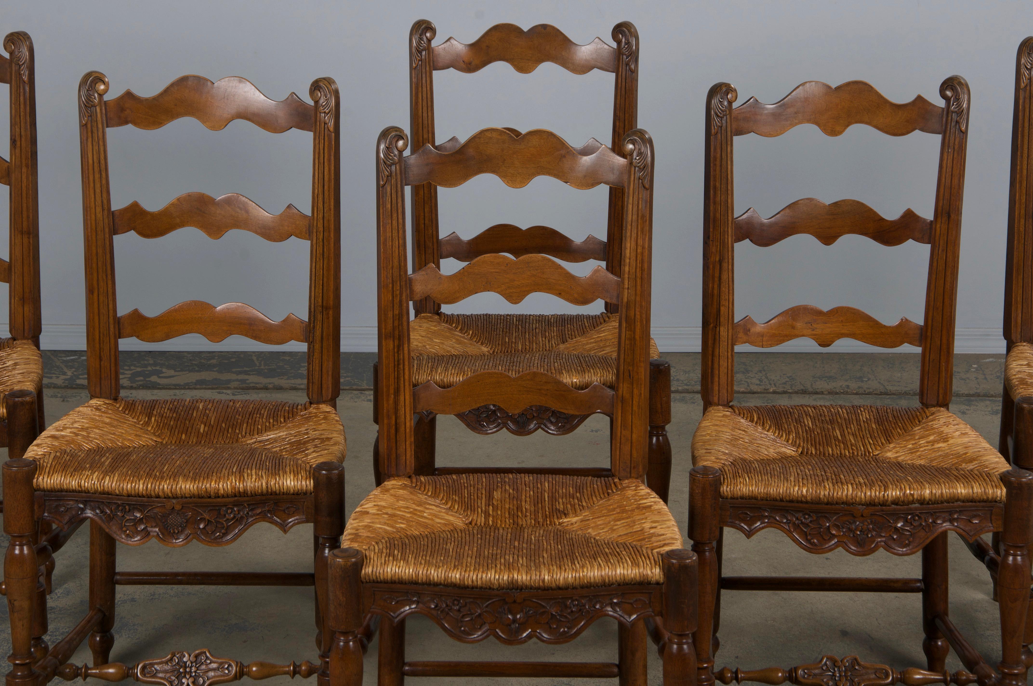 A stunning set of six late 19th-century French Provincial dining chairs, sourced from Provence, France. Expertly handcrafted from solid walnut, these chairs feature elegant ladder-back frames adorned with hand-carved acanthus leaf finials.