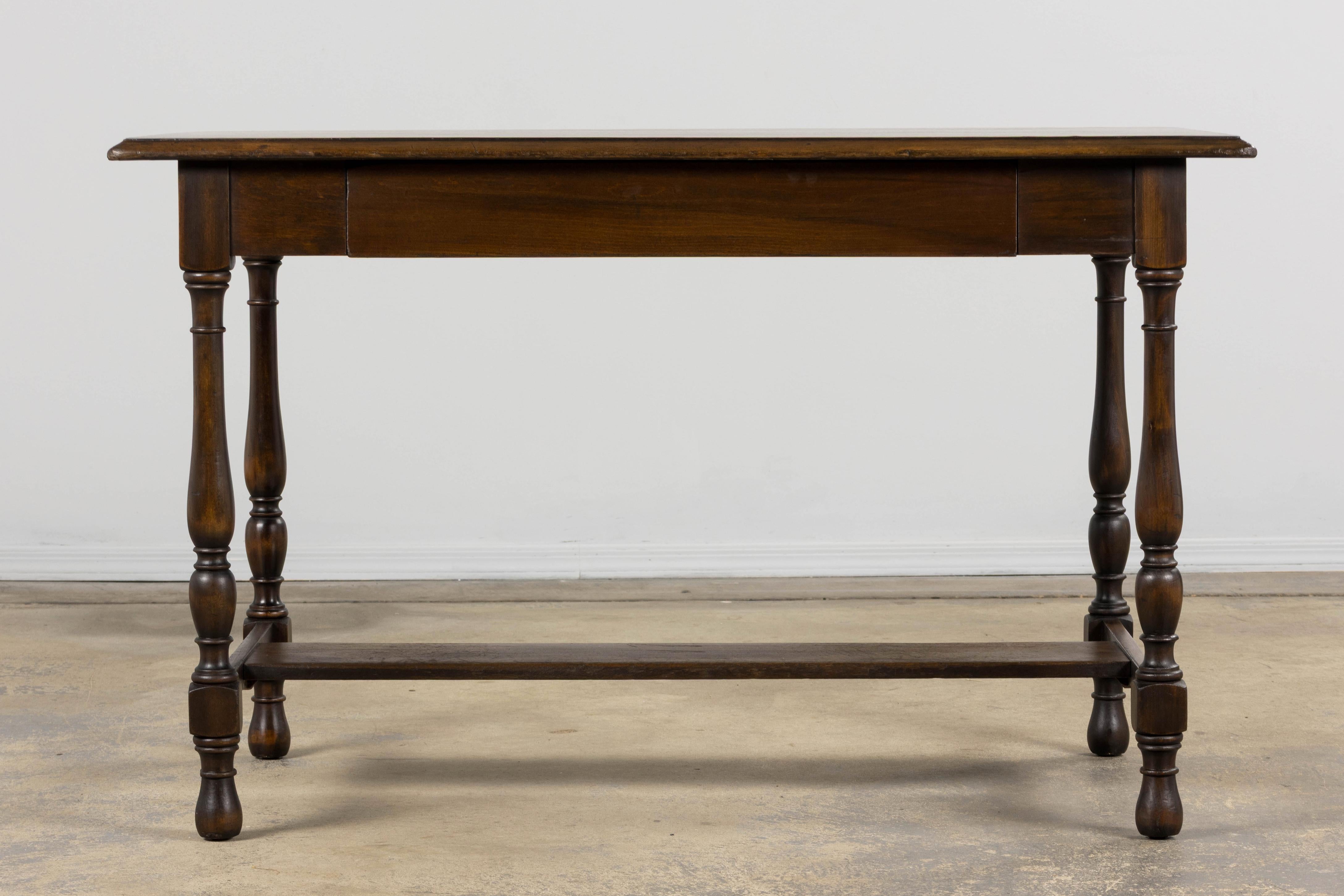 Antico tavolo da scrittura provinciale francese, proveniente dalla Provenza, Francia. Realizzato in legno di acero, il tavolo presenta una patina scura e profonda sviluppata nel tempo. Il piano rettangolare è sorretto da gambe tornite unite da