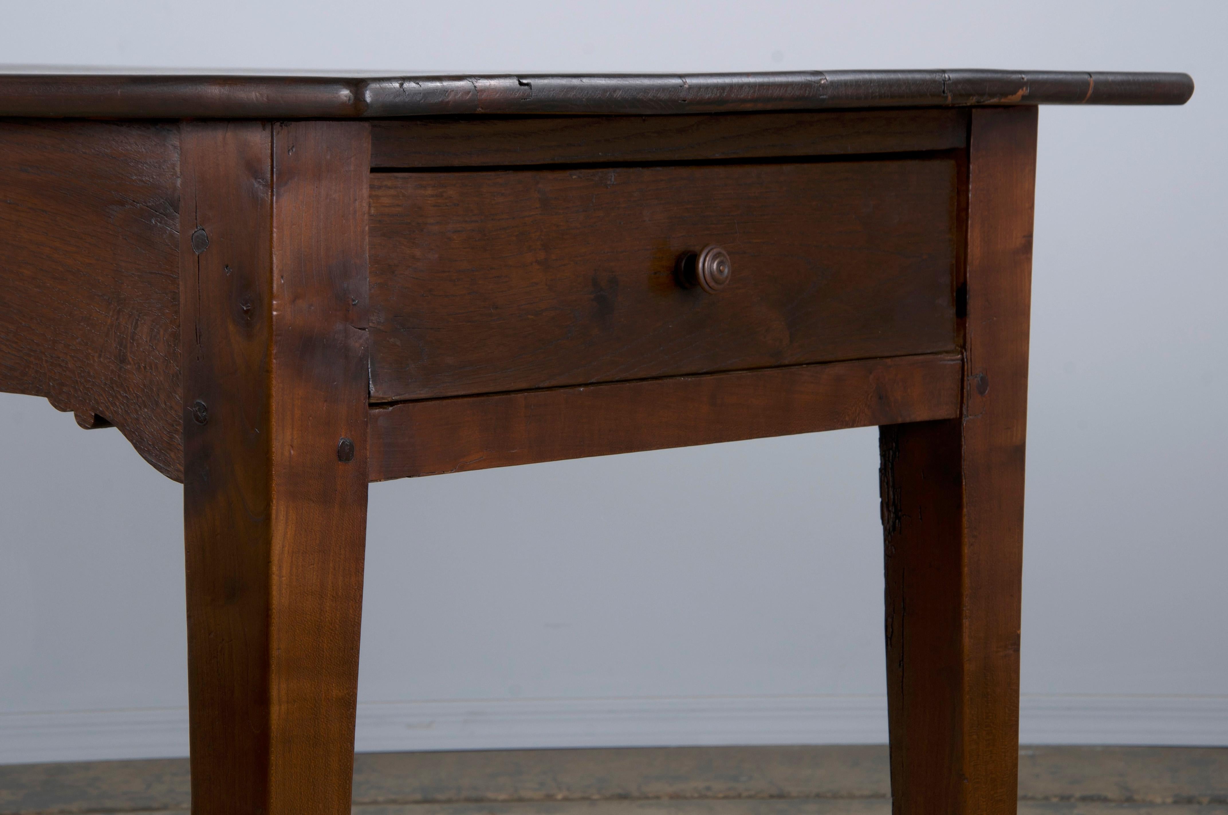 A late 19th-century French Country farmhouse dining or kitchen table, sourced from Provence, France. Handcrafted from solid mixed woods, it showcases a rich dark brown patina. The table features a 5'7