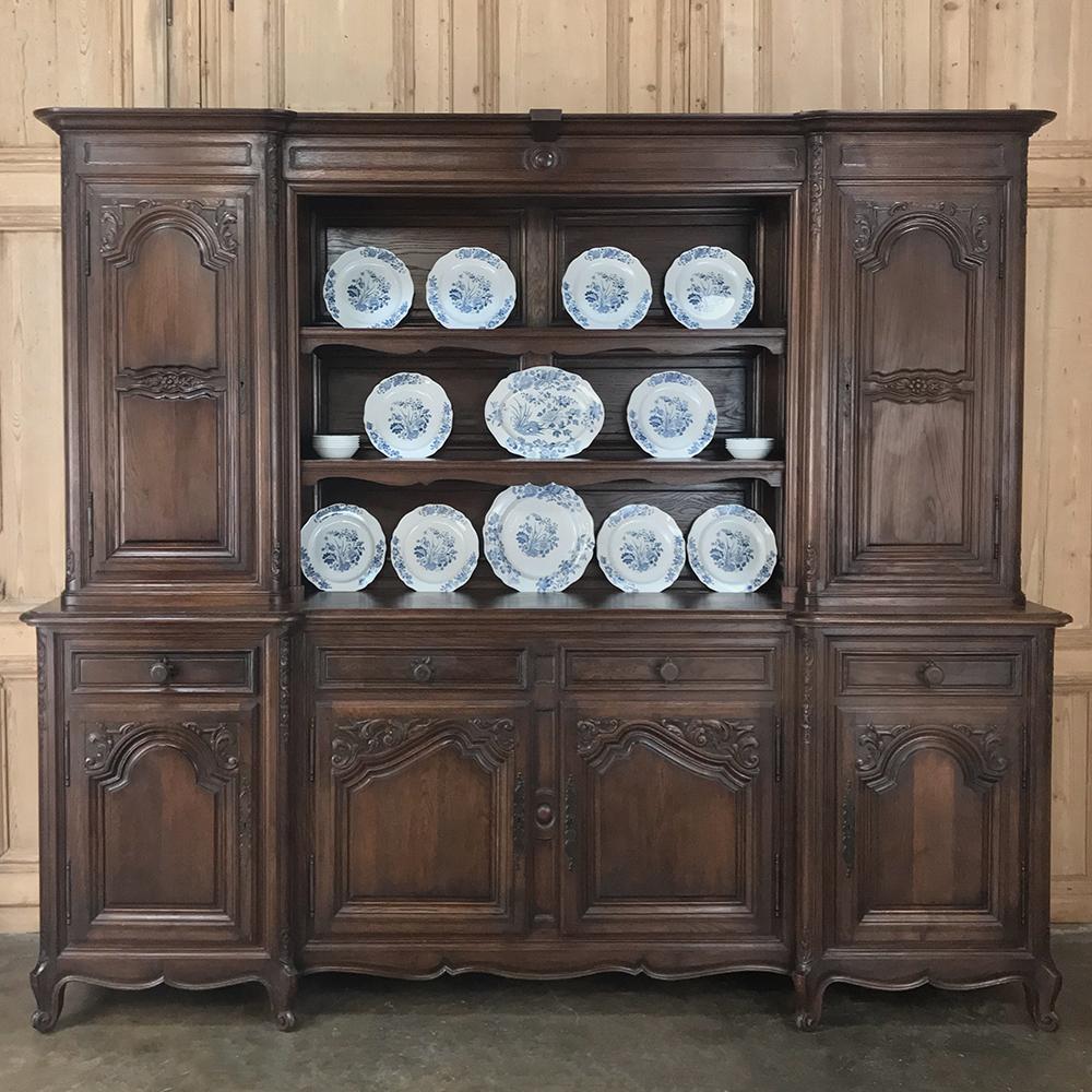 Antique country French Provincial vaisselier, buffet is a wonderful piece that combines storage, serving surface and display, all in one! Crafted on a grand scale, it features hand carved shell and foliate motifs adorning the step-back four door