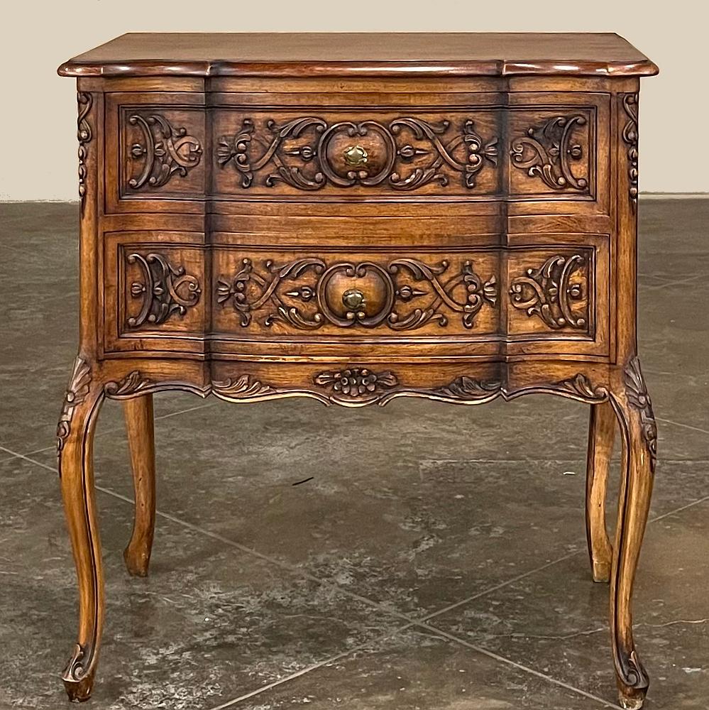 Antique Country French Walnut Commode features the stylish flair of the Louis XV genre but in a more symmetrical, restrained expression. The contoured facade creates a three panel effect, with stylized foliates and scrollwork intertwined across the